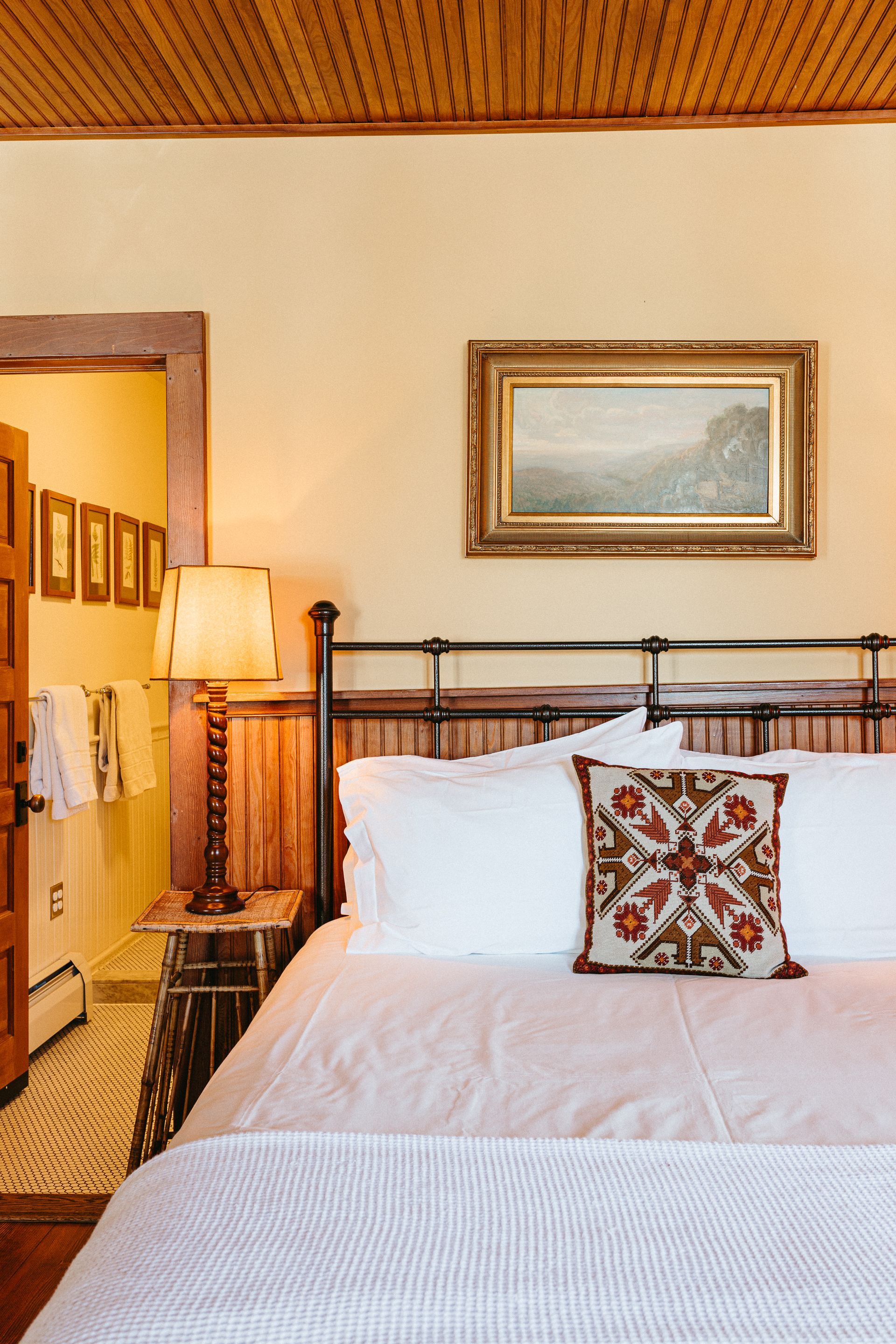 A bedroom with a bed , lamp , and painting on the wall.