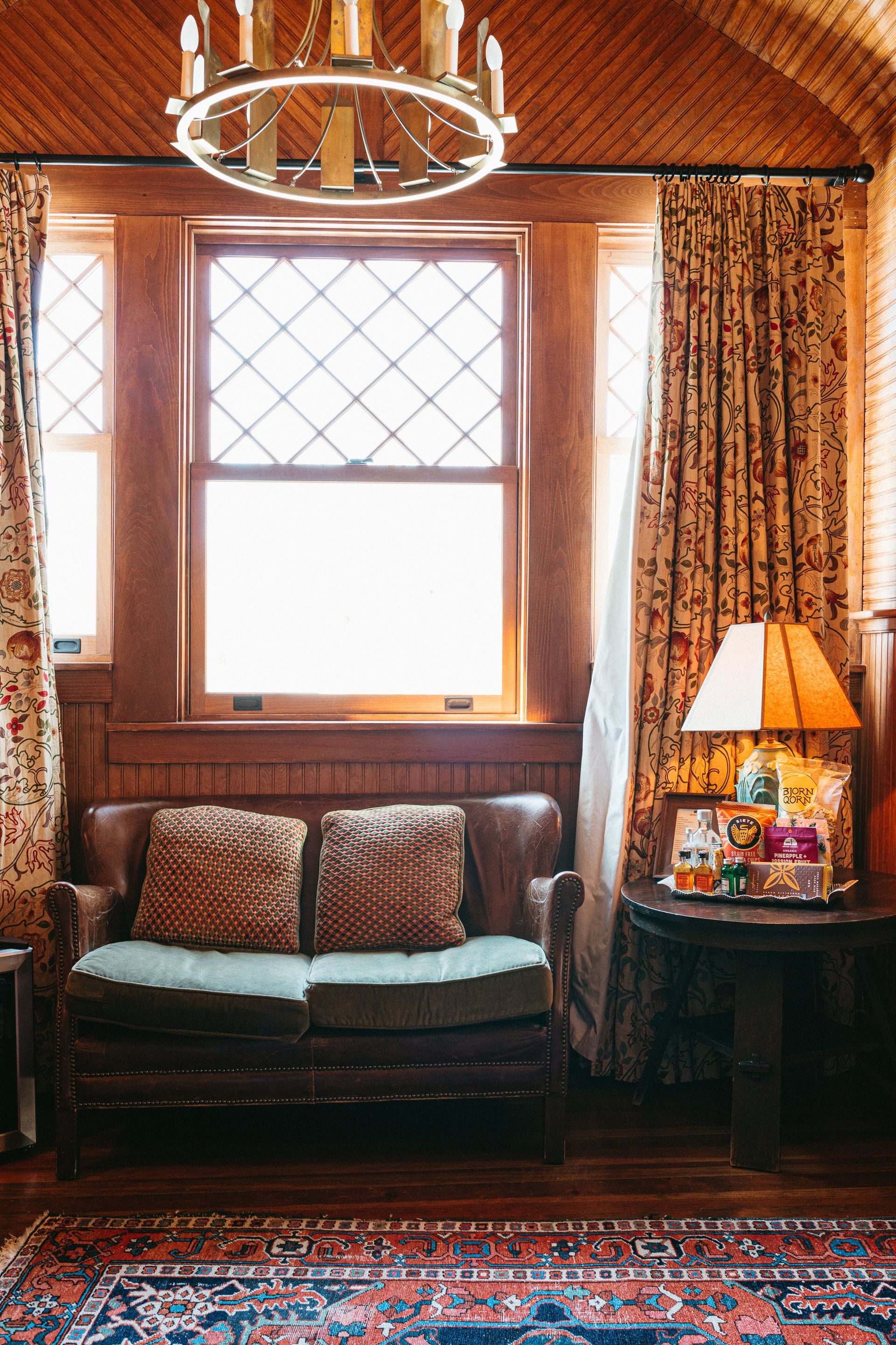 A living room with a couch , table , lamp and window.