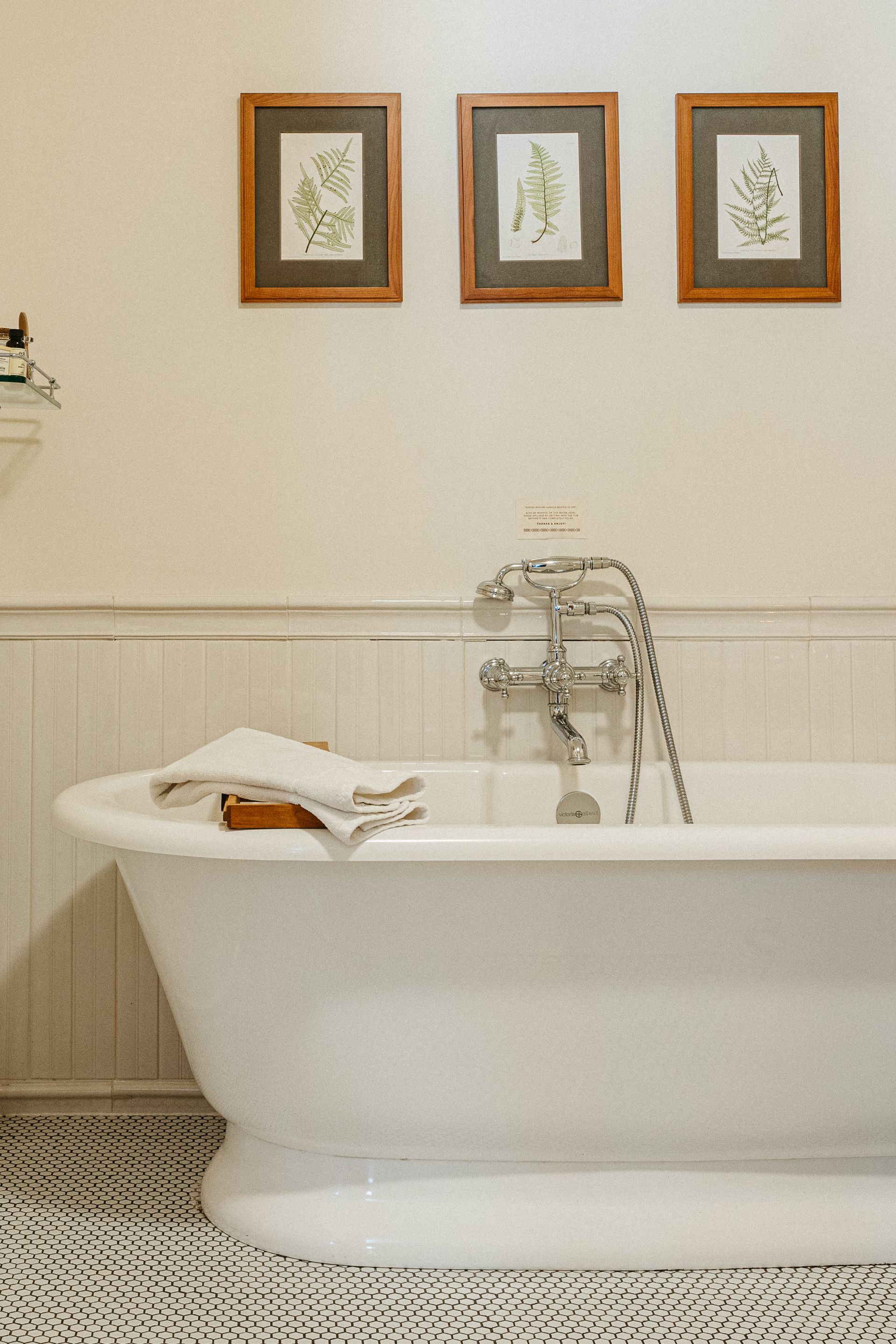 A bathroom with a bathtub and three framed pictures on the wall