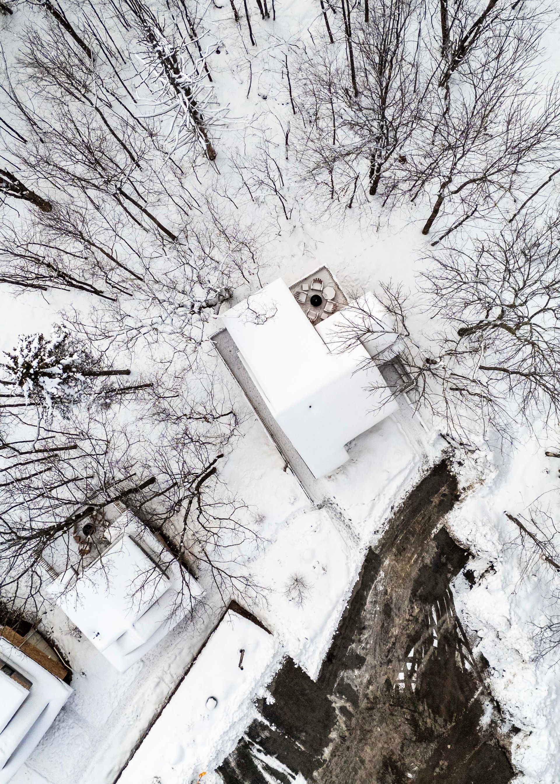 An aerial view of a snowy forest with houses and trees covered in snow.