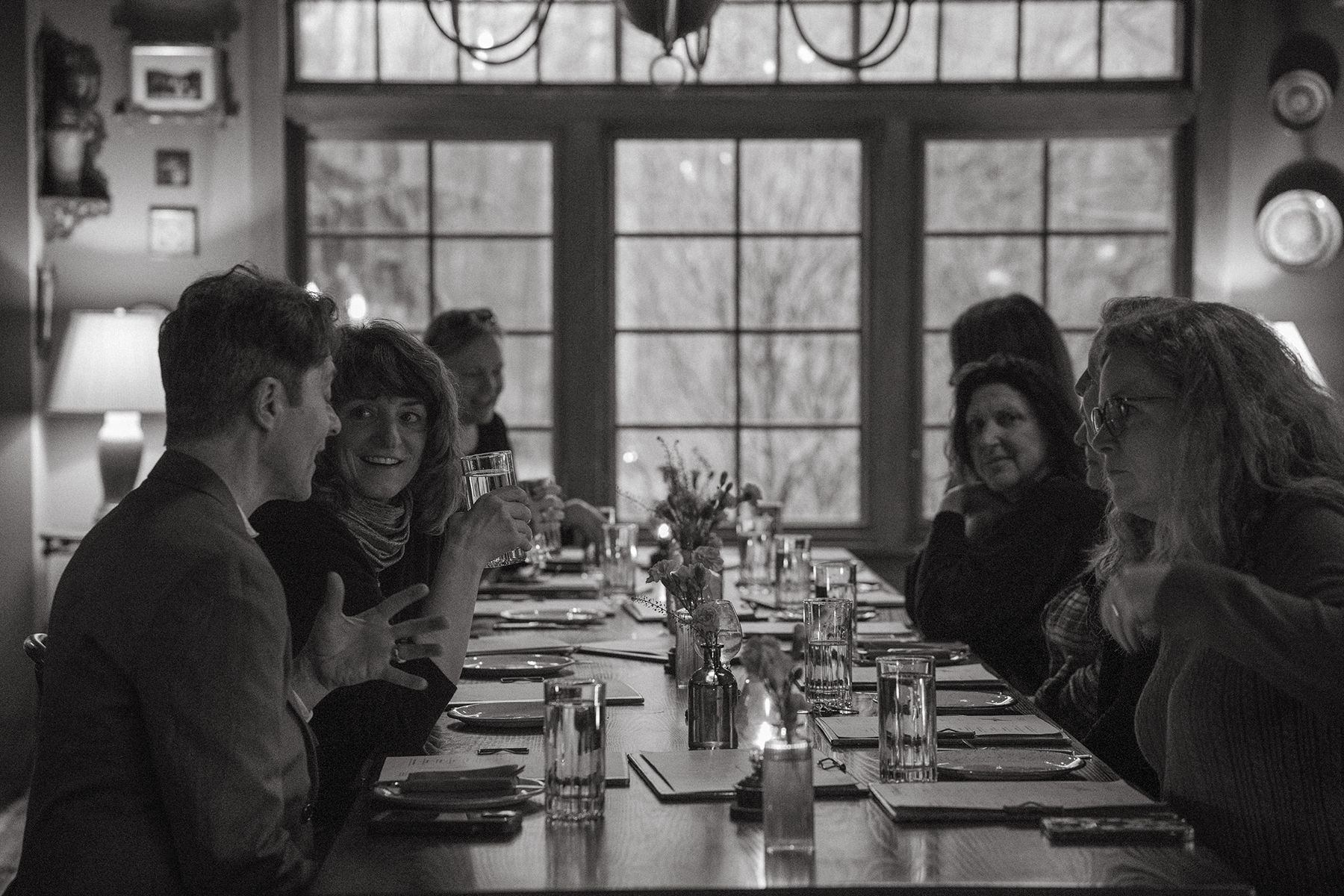 A black and white photo of a group of people sitting at a long table.
