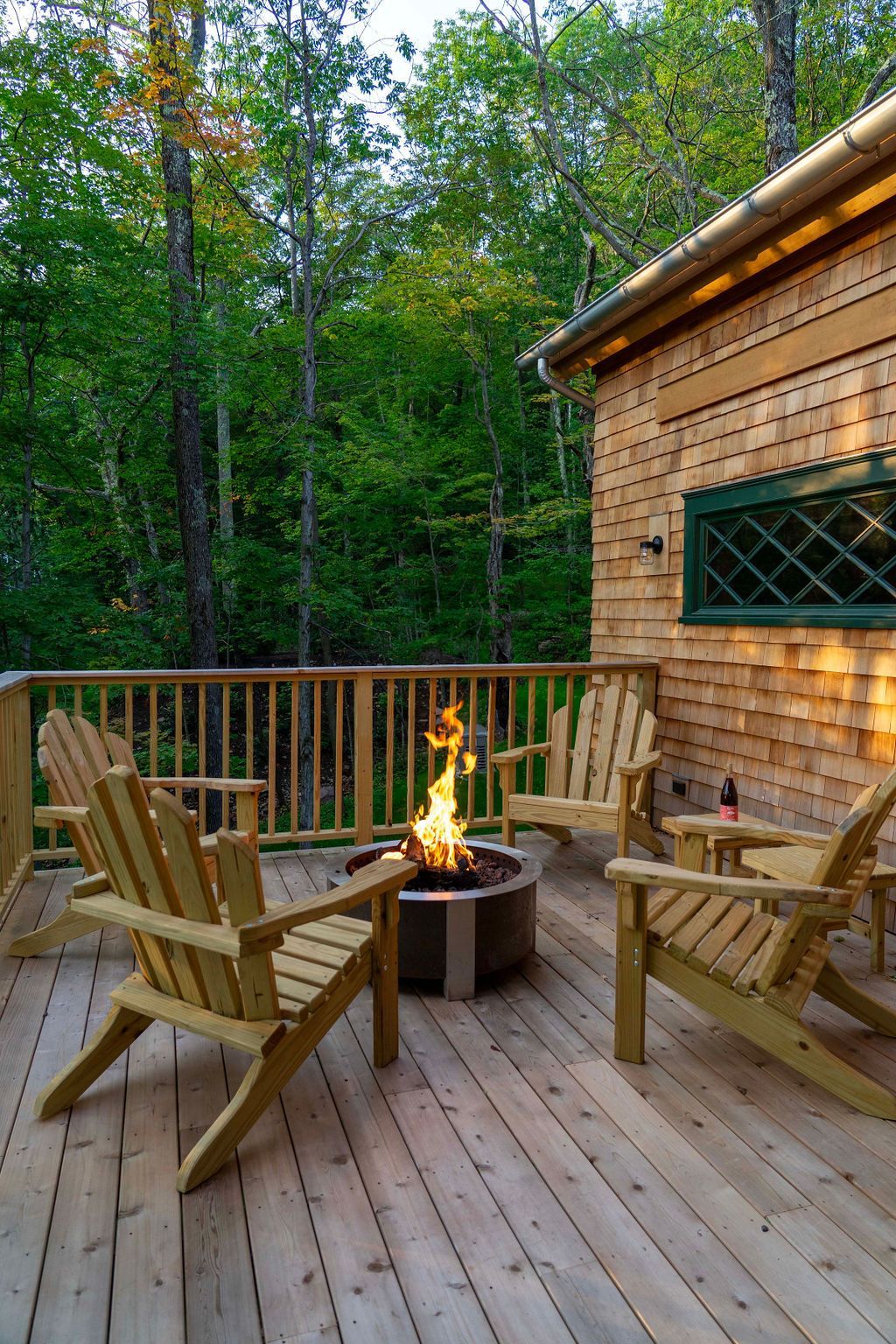 There is a fire pit on the deck with chairs around it.
