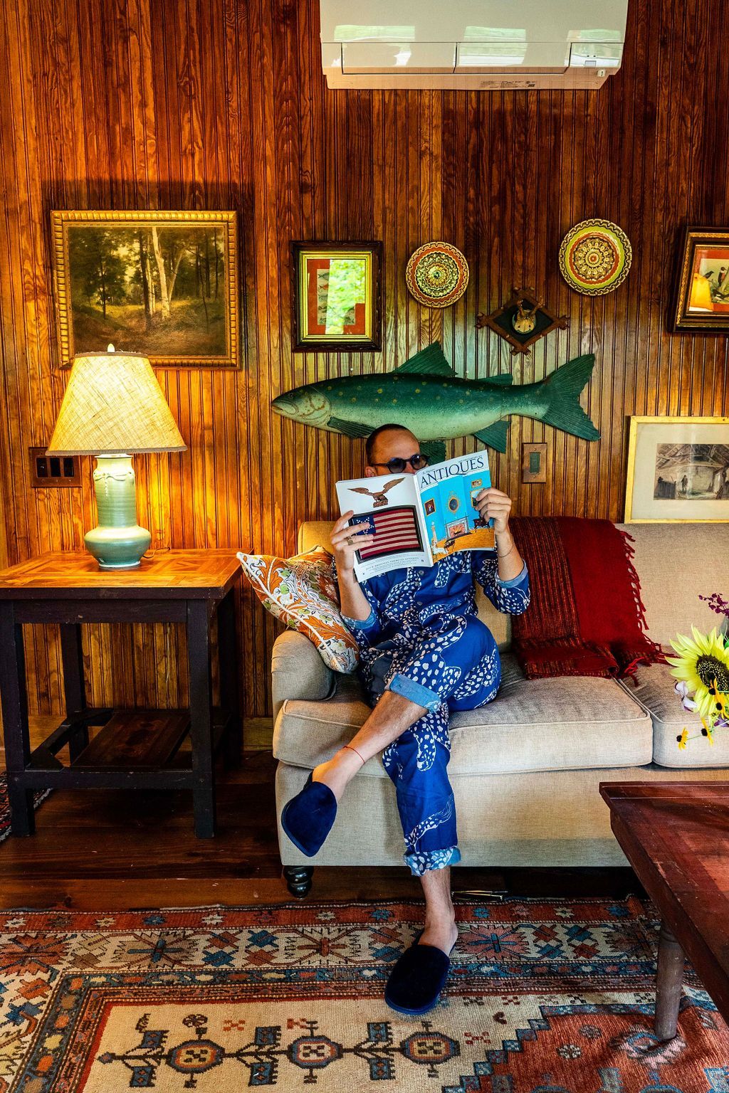 A man is sitting on a couch reading a magazine.
