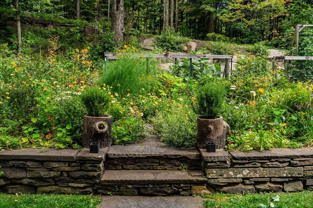 A stone wall with steps leading up to a garden filled with lots of plants.