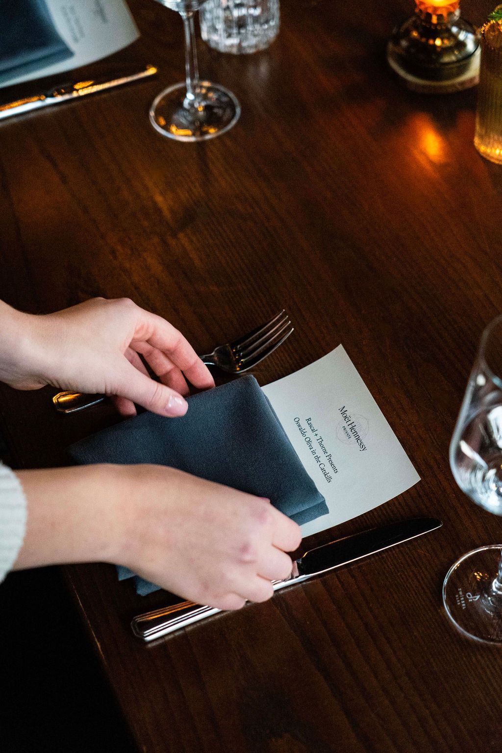 A person is holding a napkin over a menu on a table.