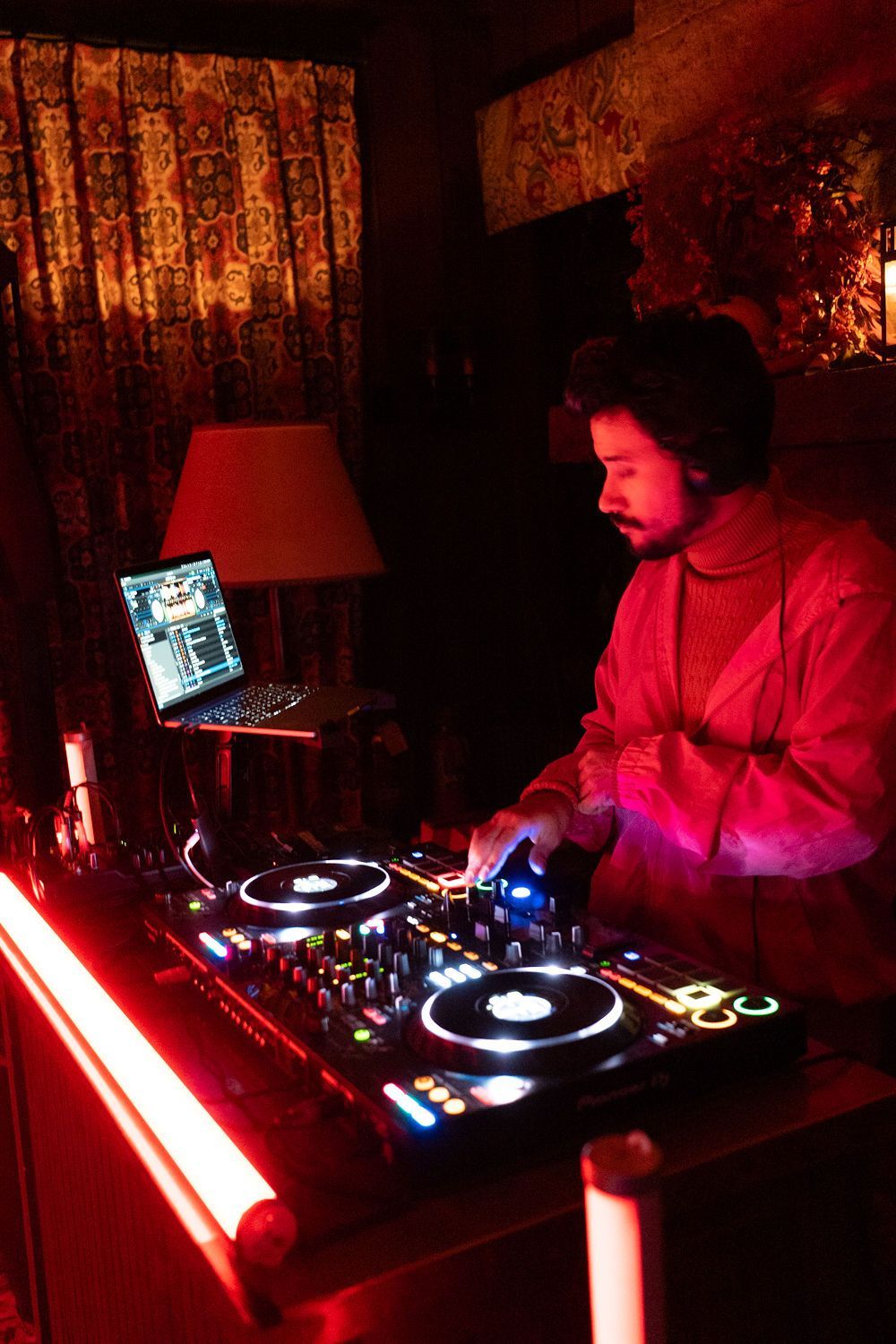 A man is playing a dj set in a dark room
