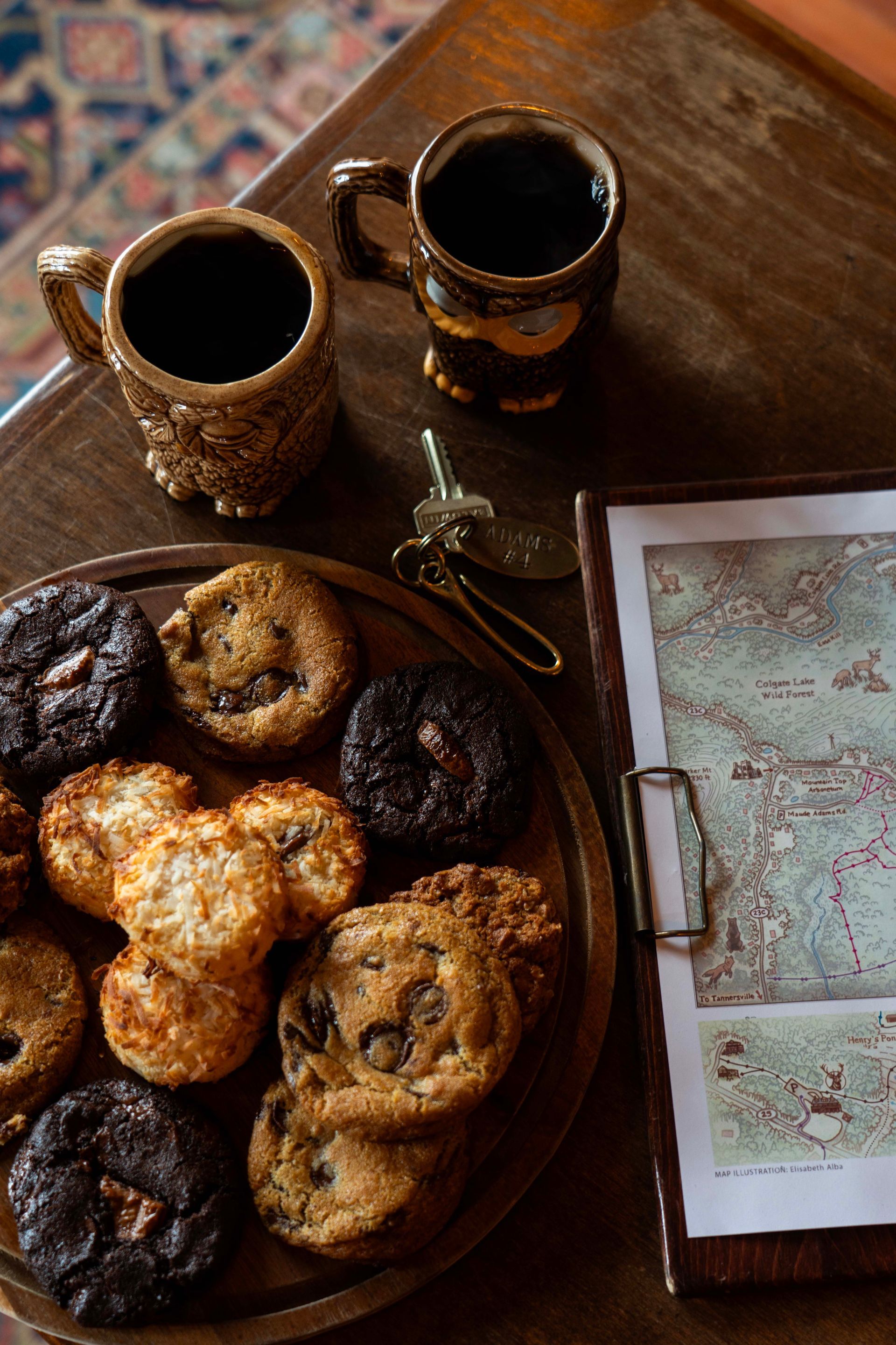 A wooden table topped with a plate of cookies and two cups of coffee.