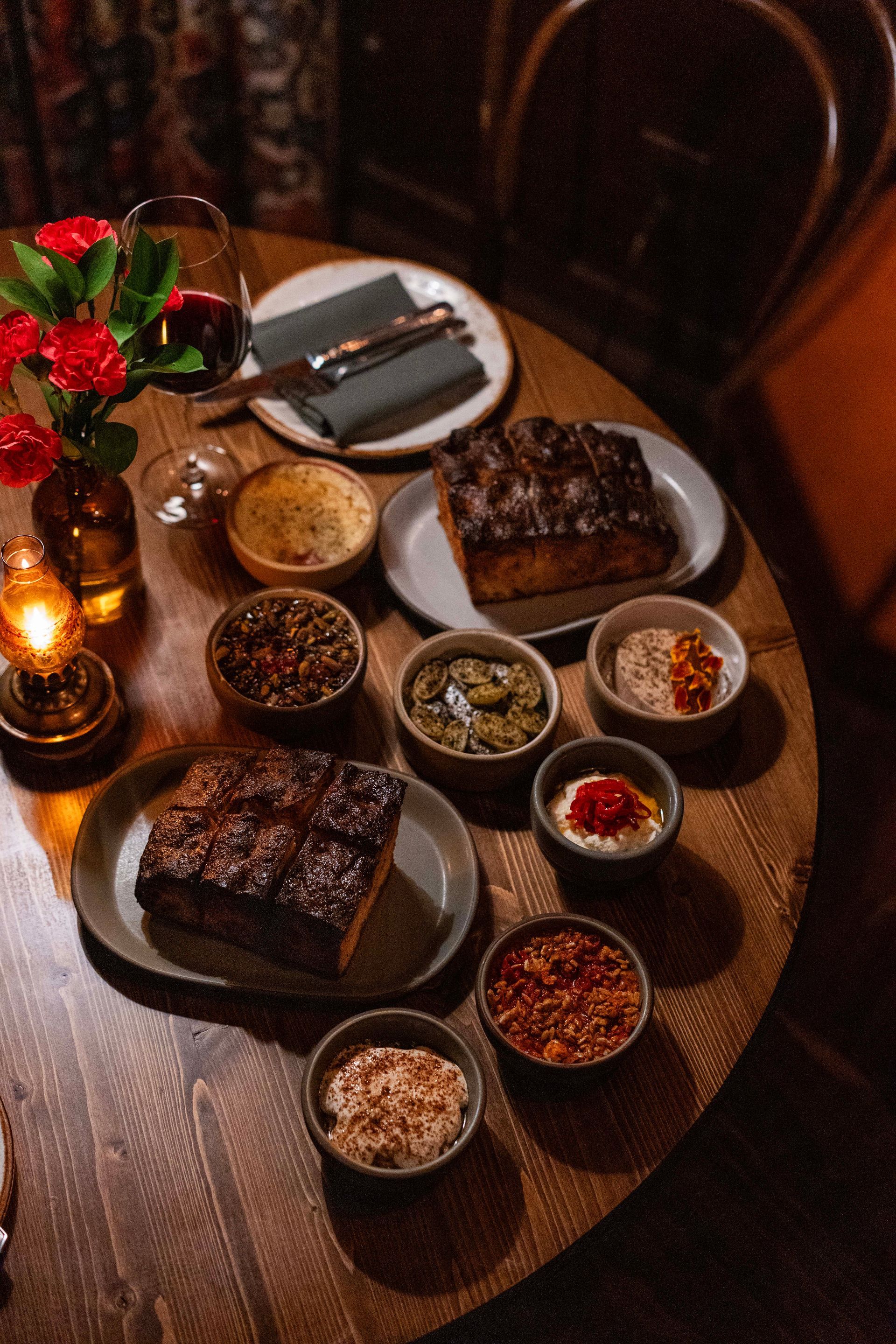 A wooden table topped with plates of food and bowls of sauces.