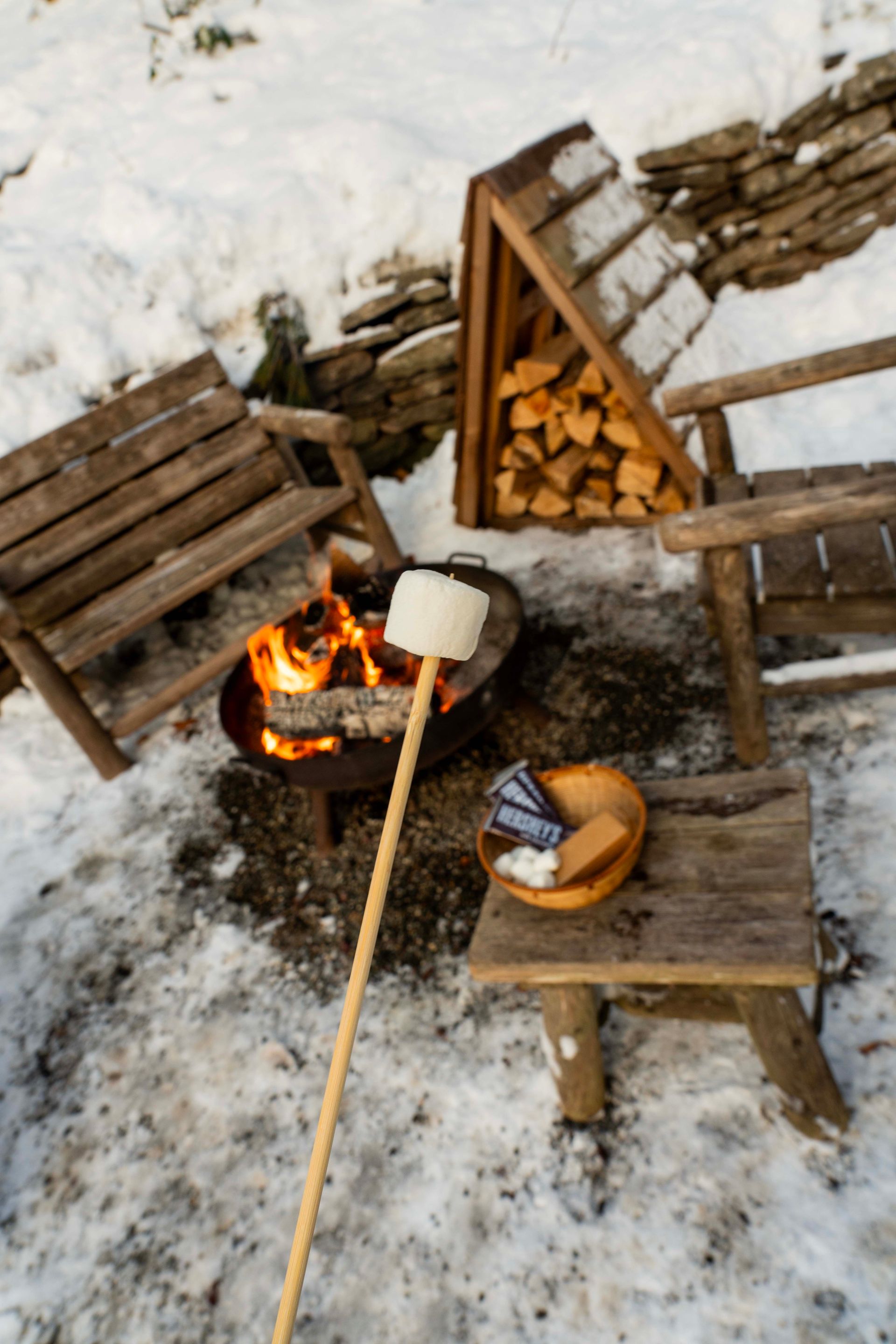 A marshmallow is being cooked over a fire pit in the snow.