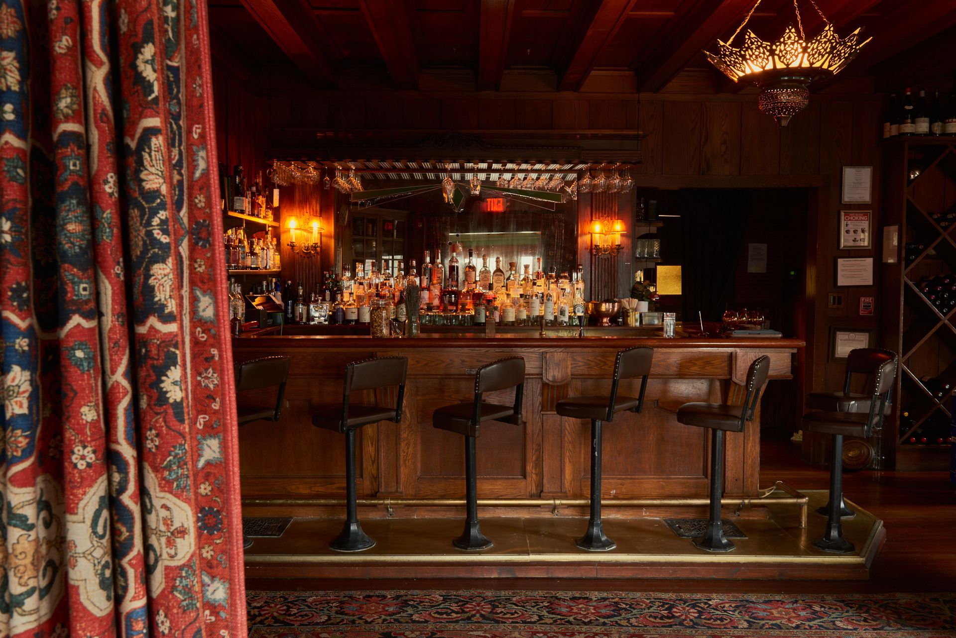 A bar with stools and a red curtain behind it