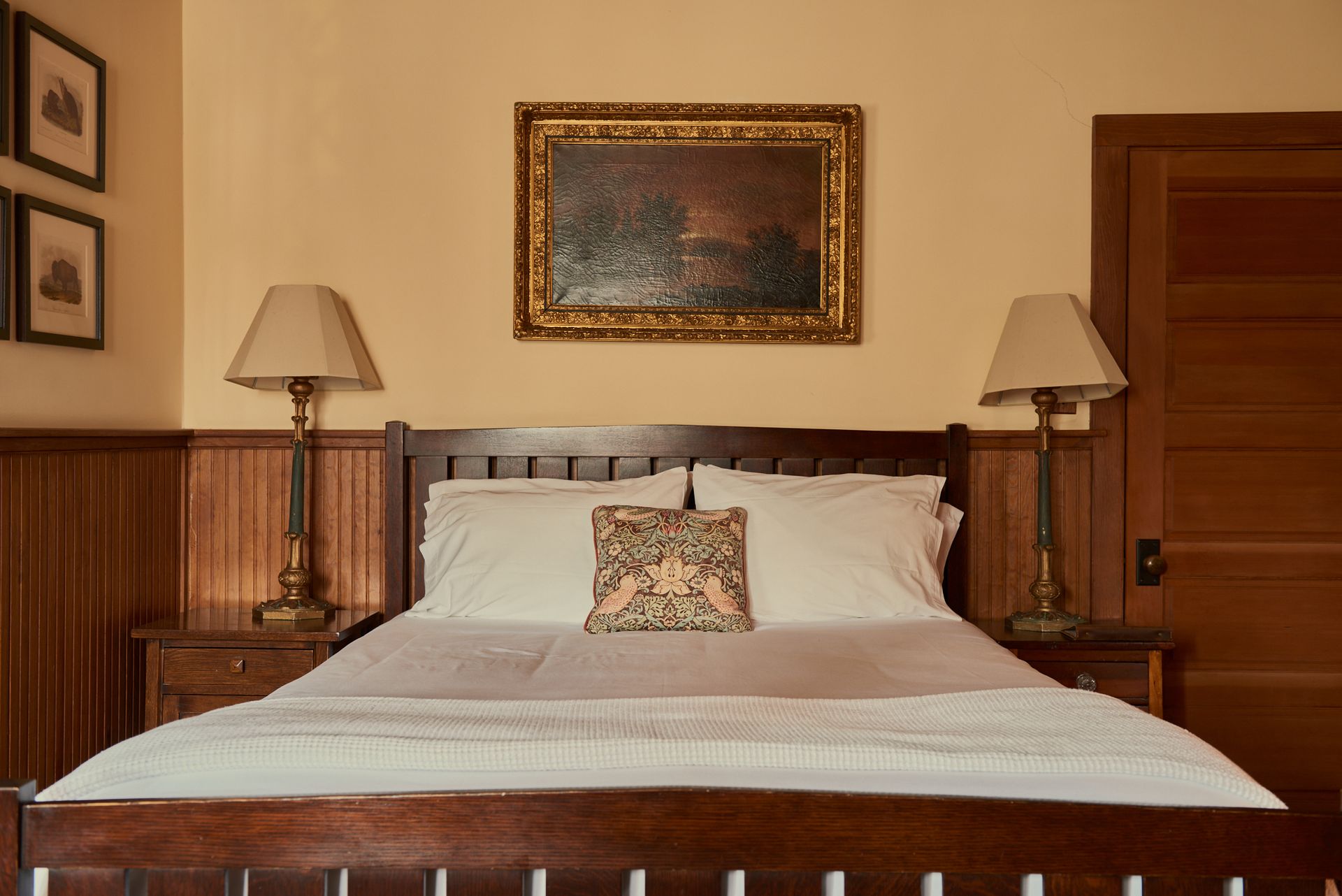 A bedroom with a bed , lamps and a painting on the wall