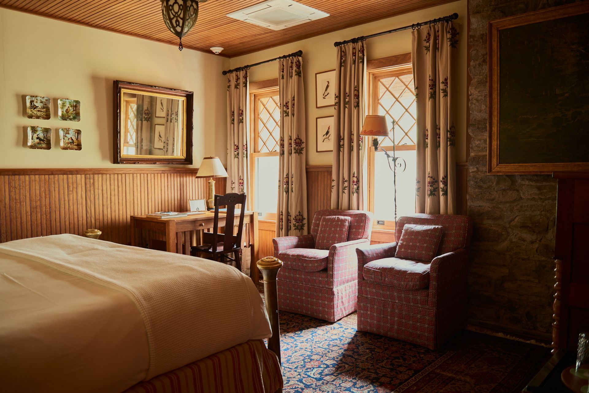 A hotel room with a bed , chairs , desk and mirror