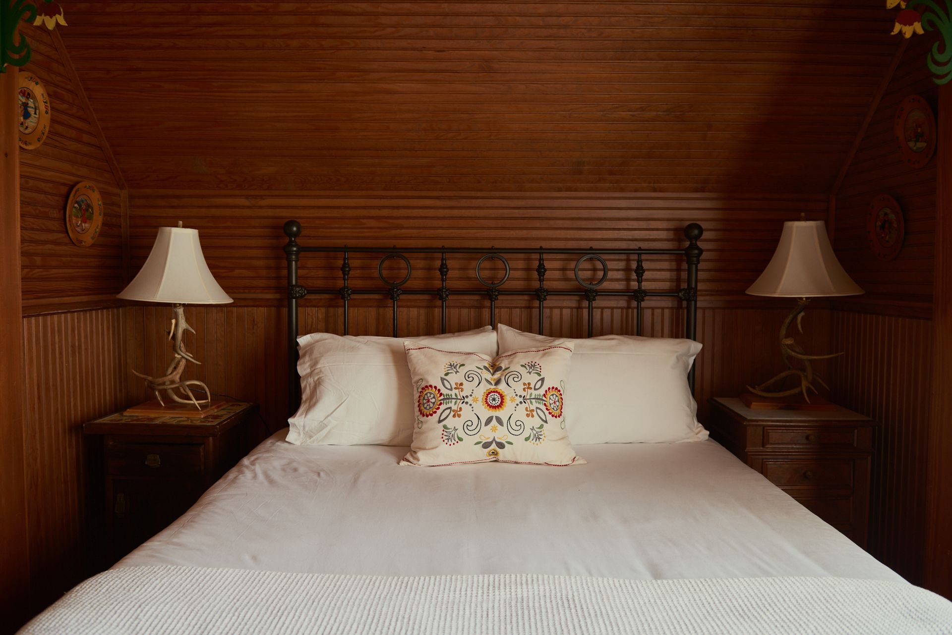 A bedroom with a bed , two lamps and a wooden wall.
