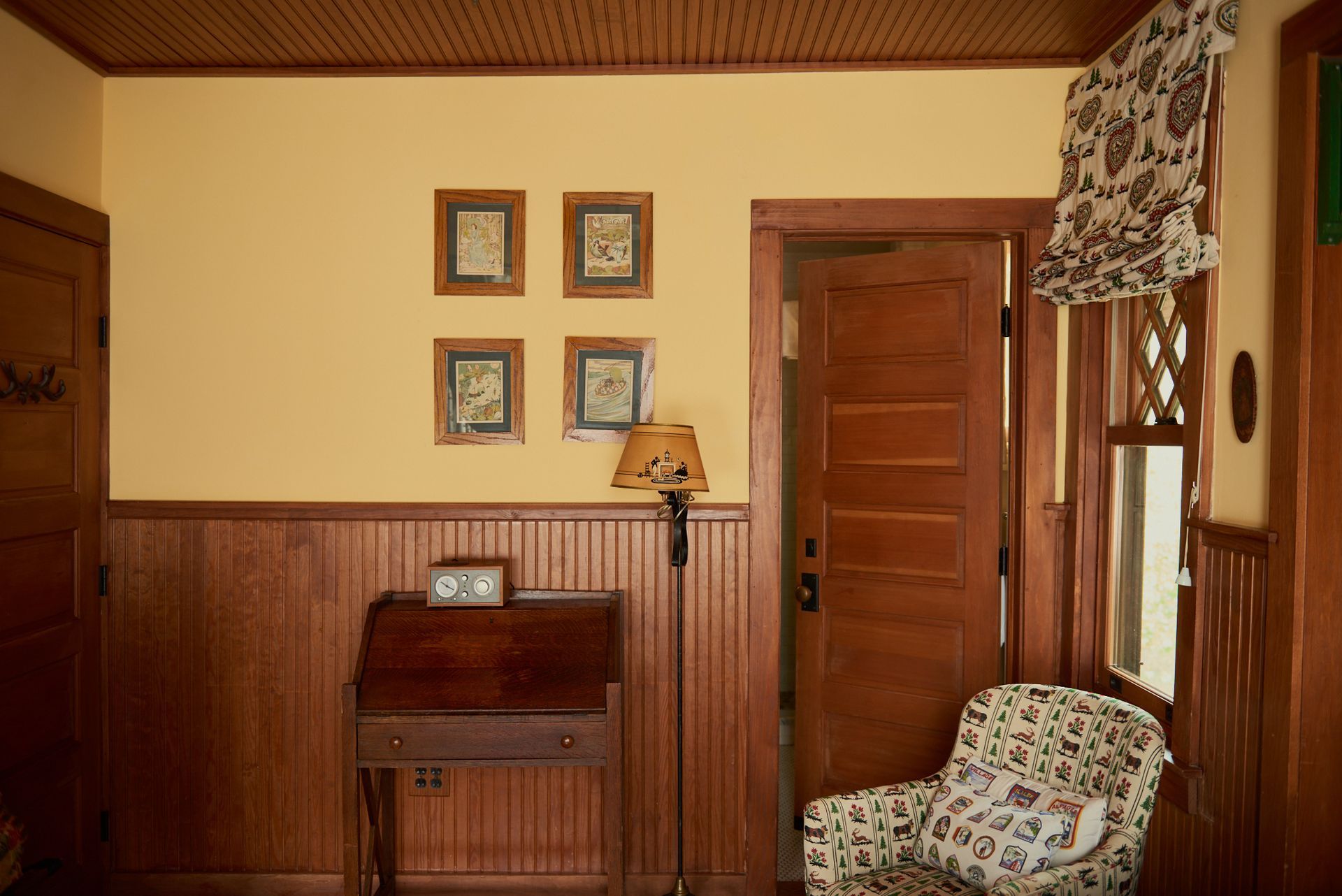 A living room with wood paneling and a chair and desk