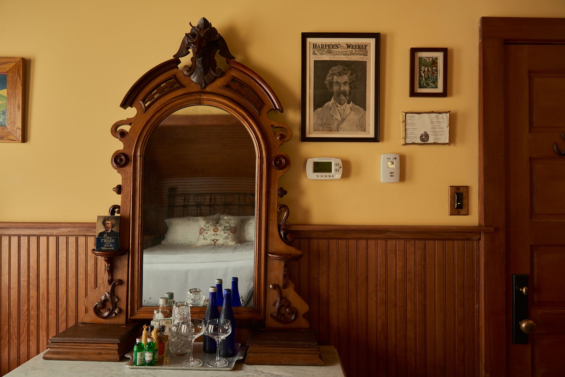 A bedroom with a large mirror and a picture on the wall above it.