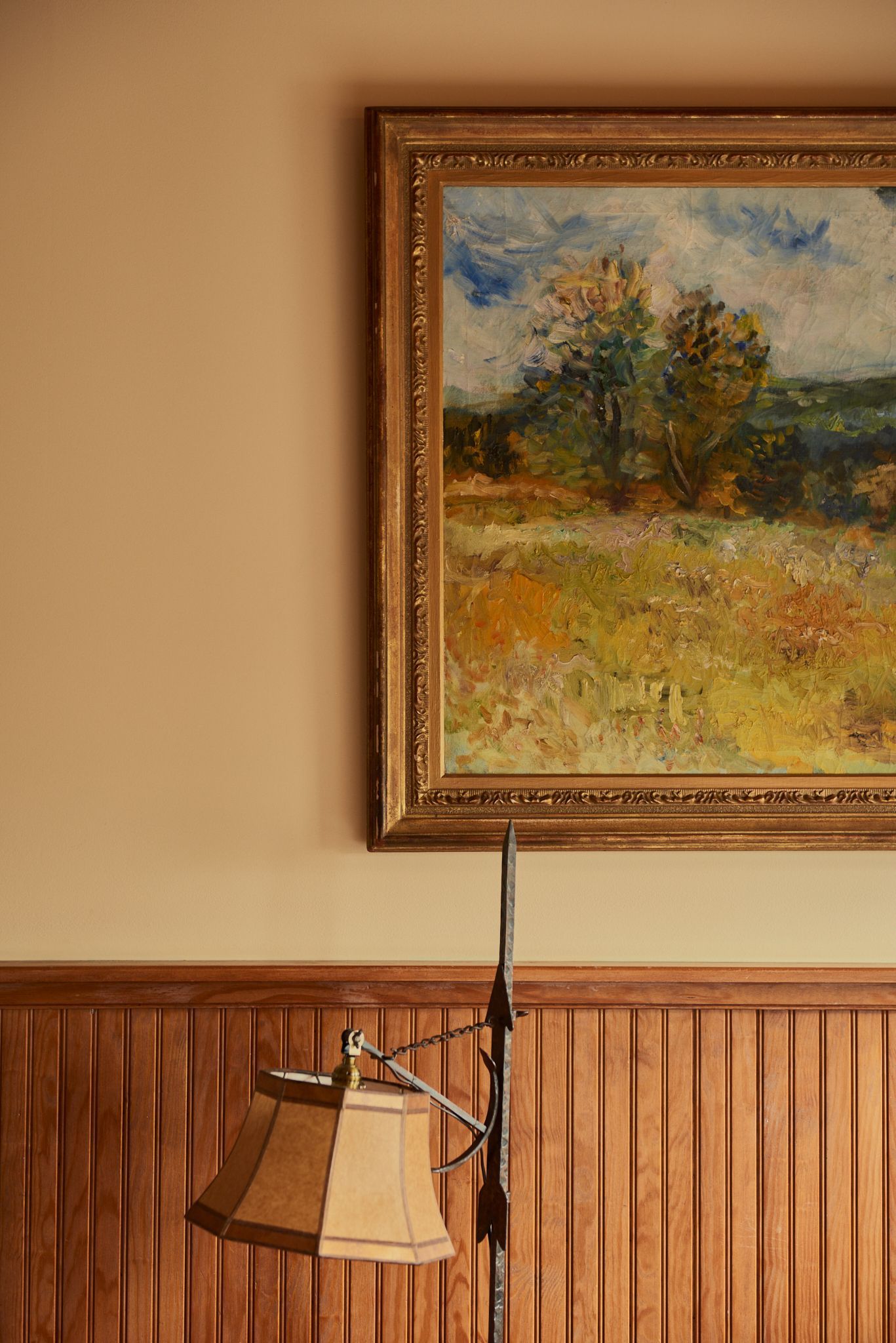 A painting is hanging on a wall next to a lamp.