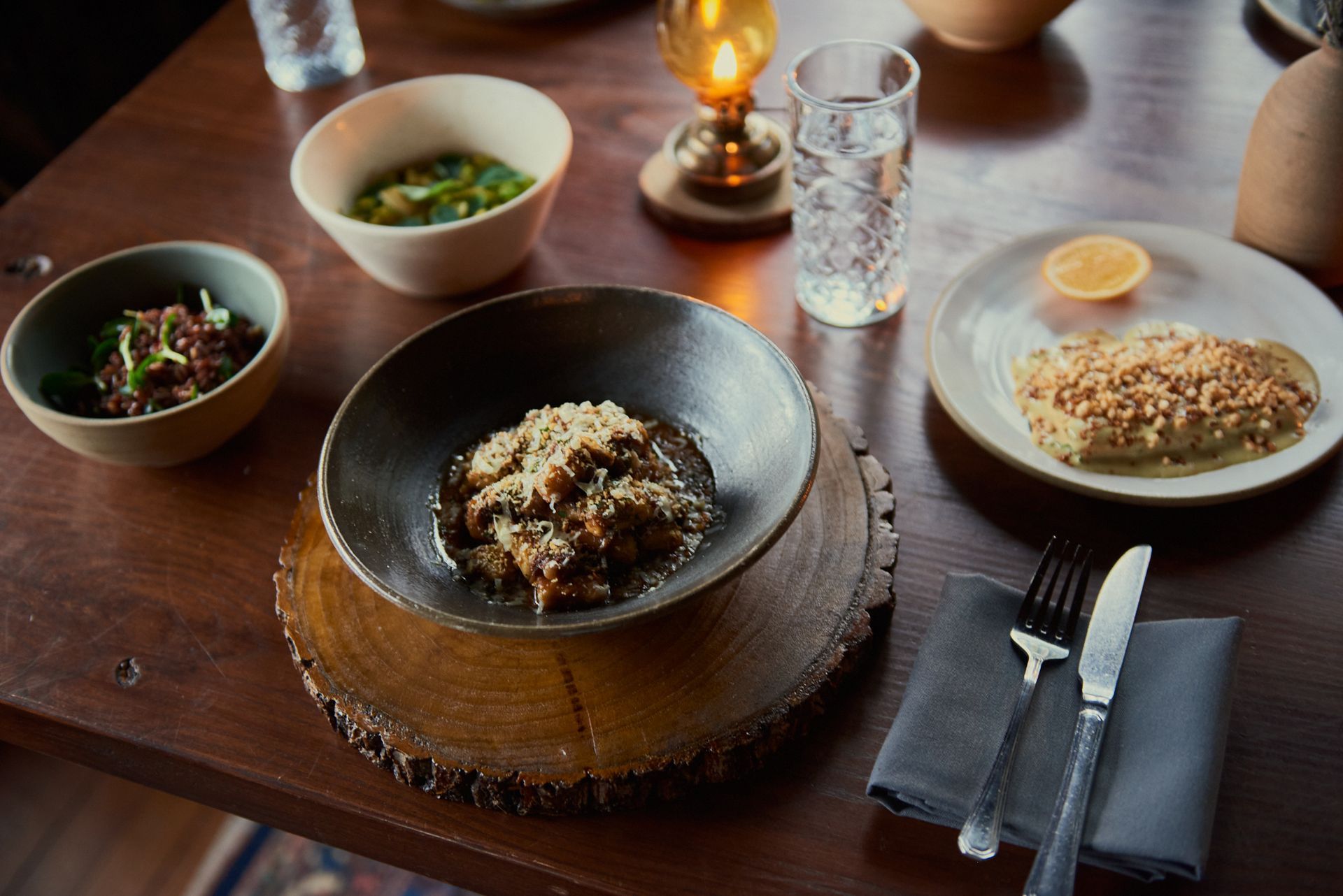 A wooden table topped with bowls of food and plates of food.