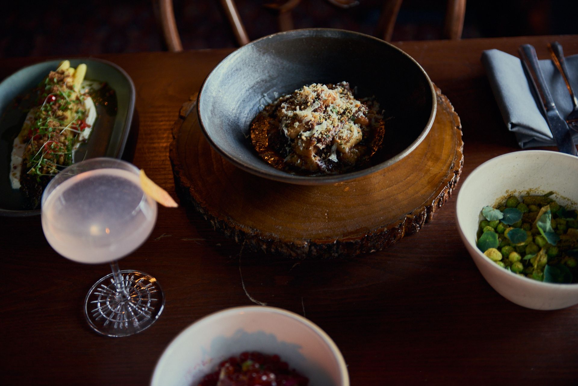 A wooden table topped with bowls of food and drinks.