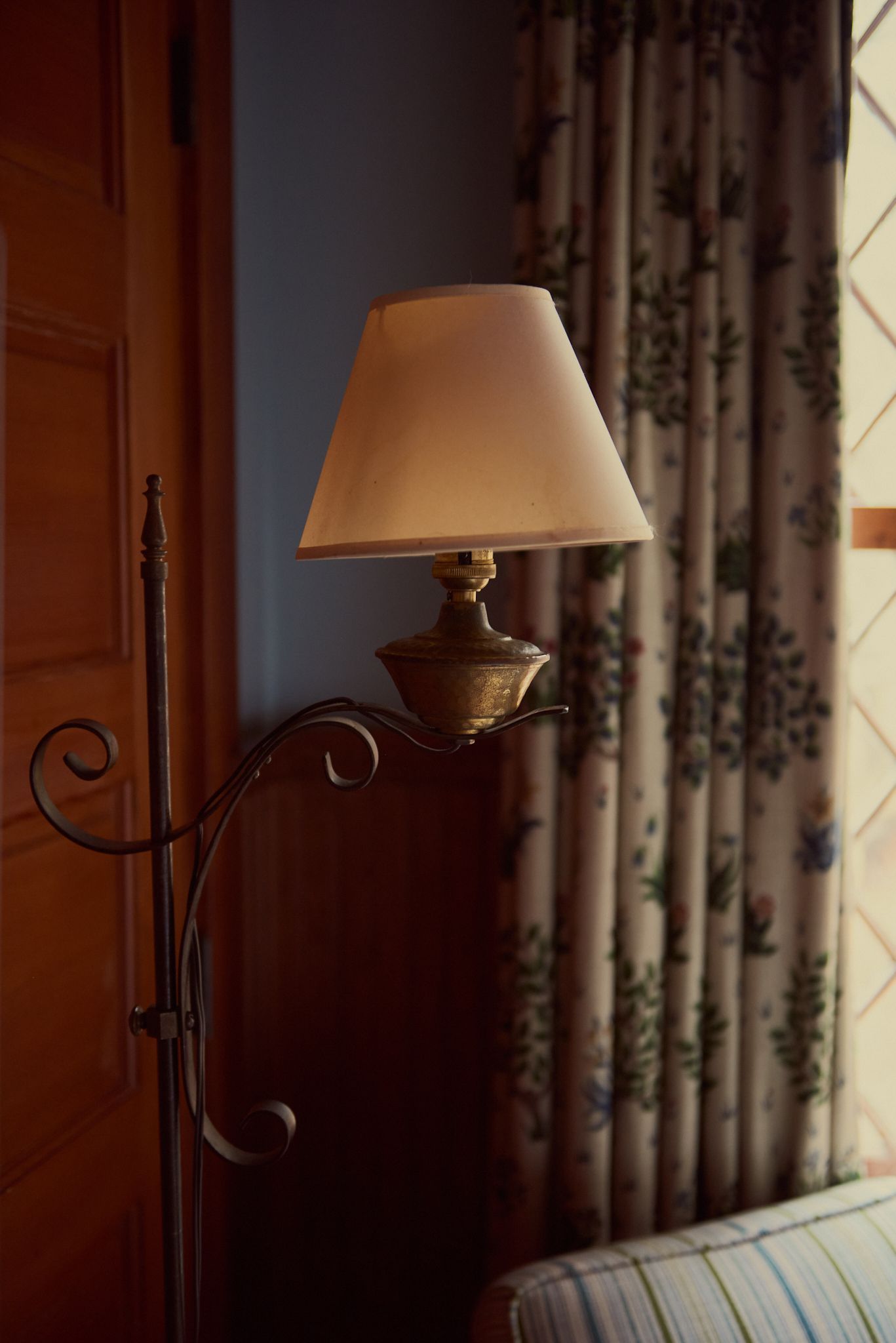 A lamp is sitting next to a window in a room.