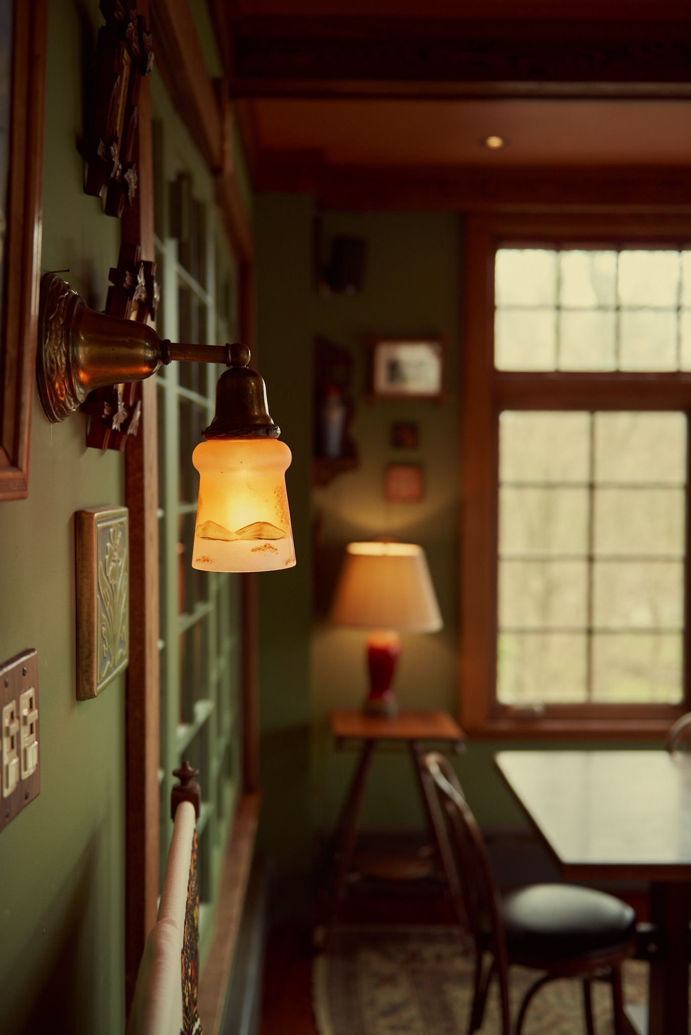 A room with a table and chairs and a lamp on the wall.