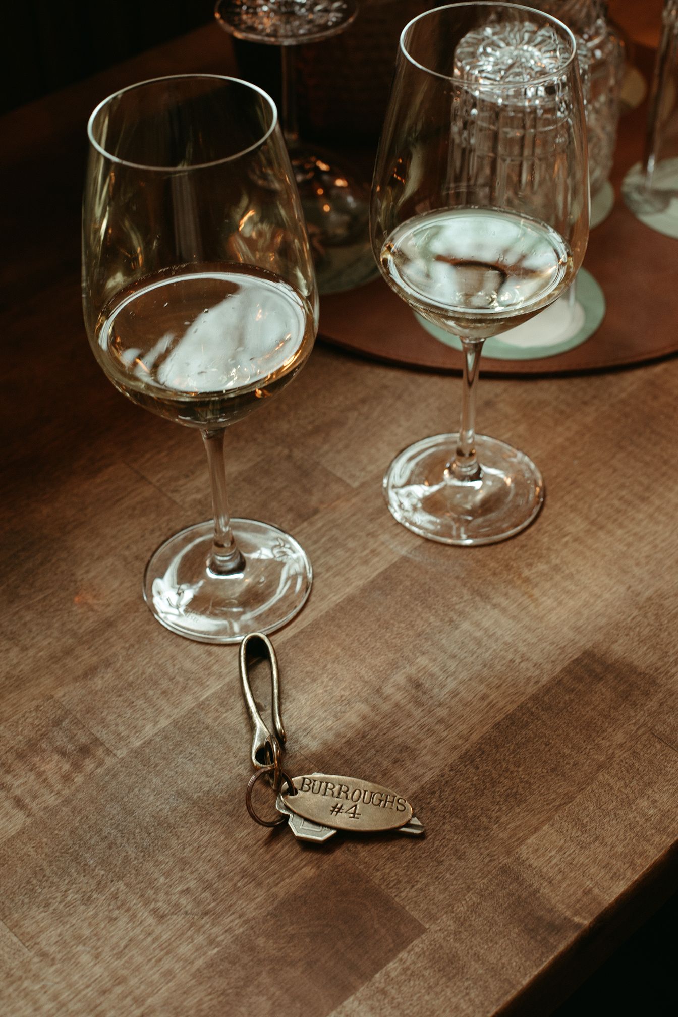 Two wine glasses and a key on a wooden table.