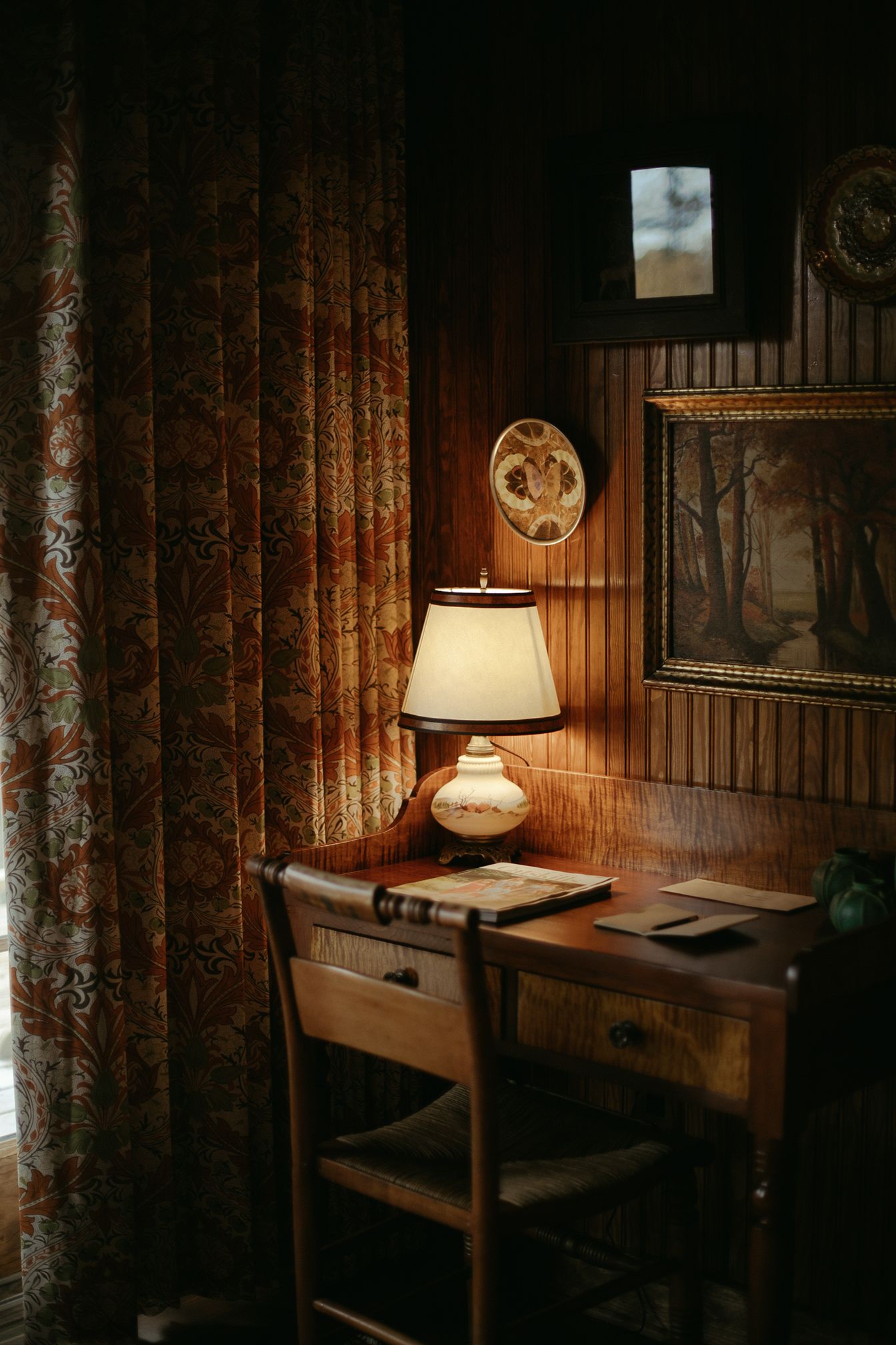 A desk with a lamp and a chair in a dark room.