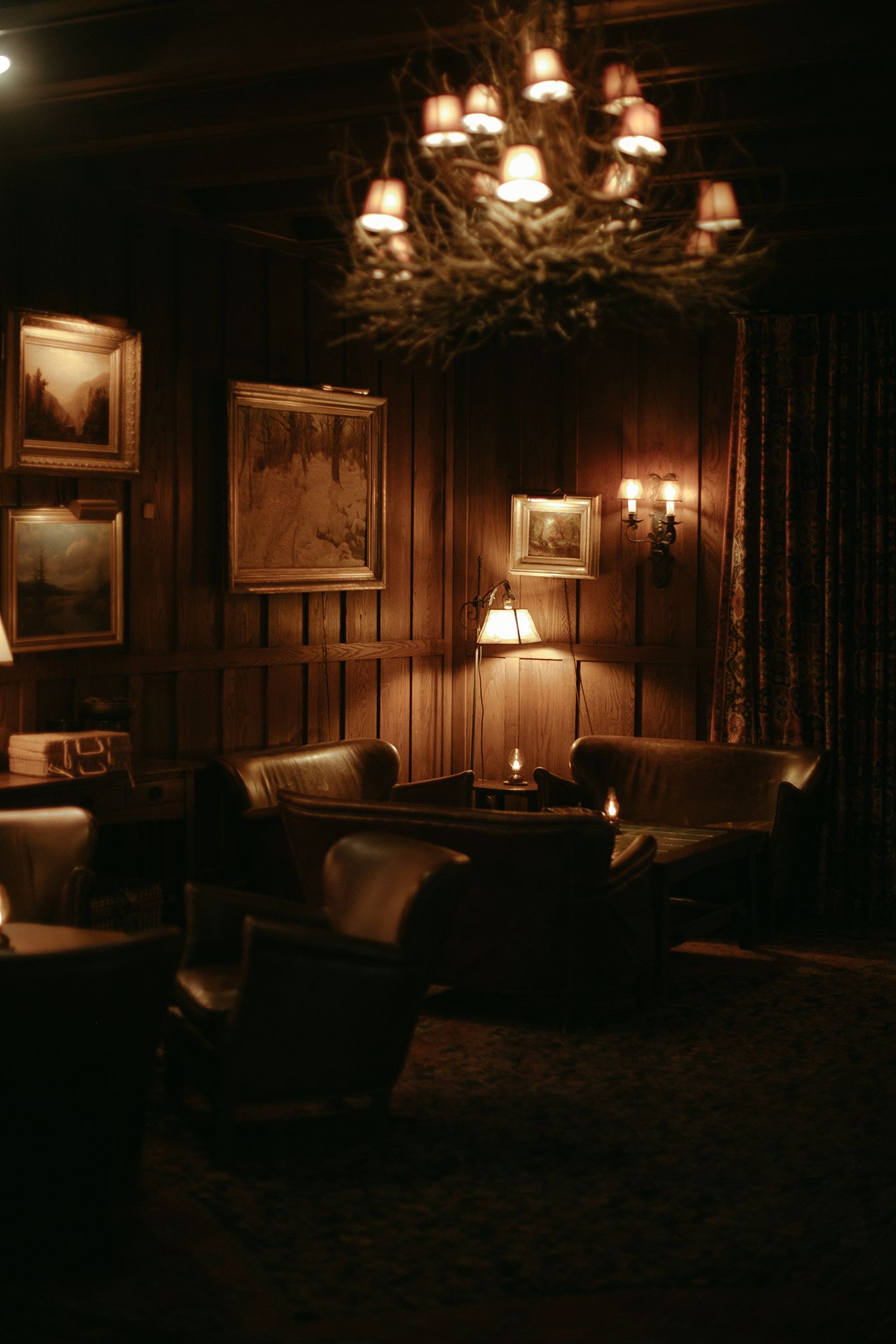 A living room filled with furniture and a chandelier in a dark room.