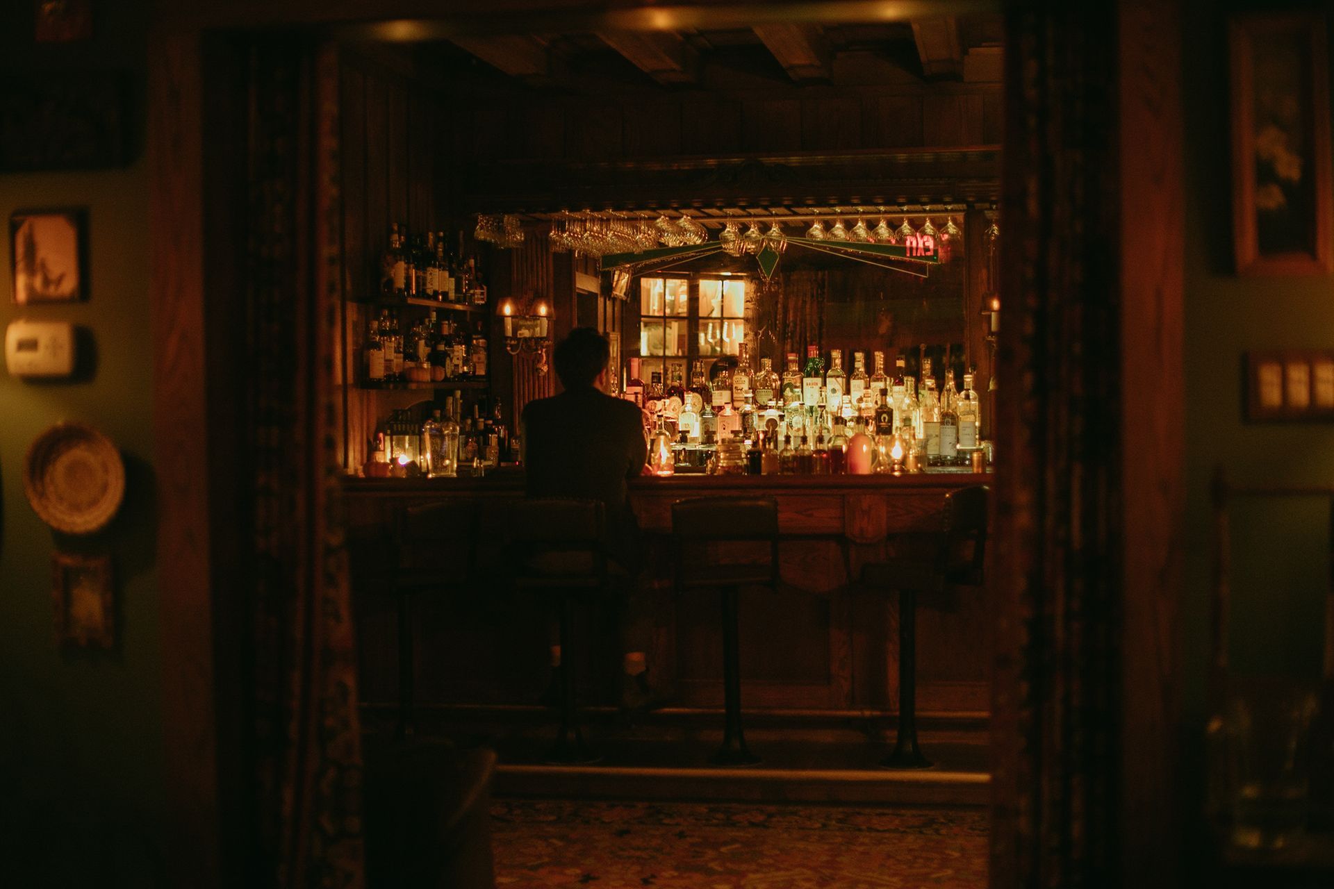 A man is sitting at a bar in a dark room.