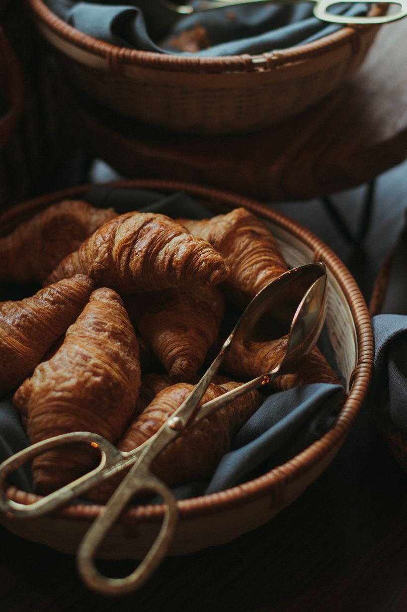 A bowl of croissants with scissors and tongs in it