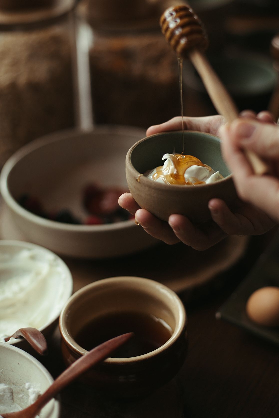 A person is pouring honey into a bowl of food.