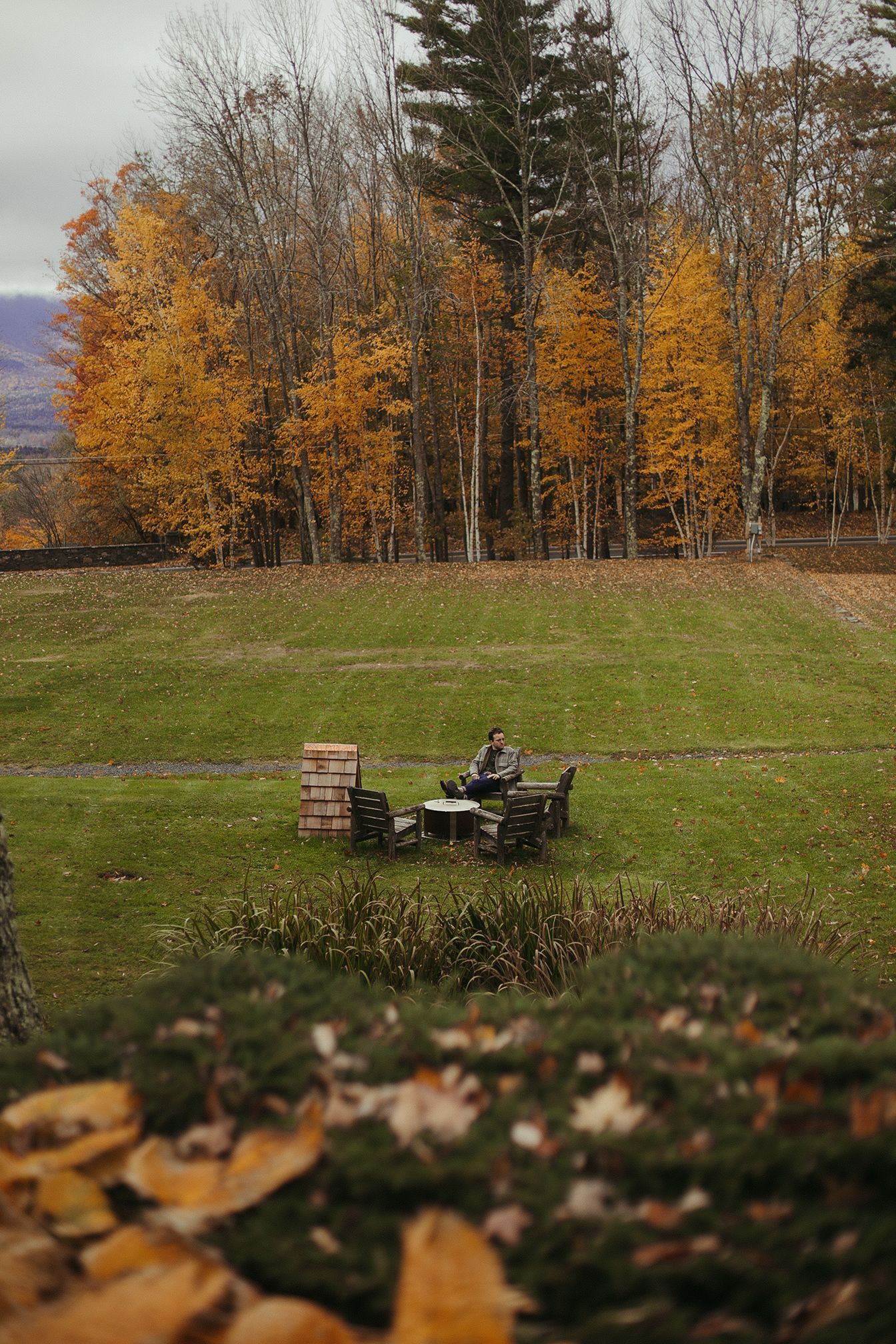 A group of people are sitting around a fire pit in a field.