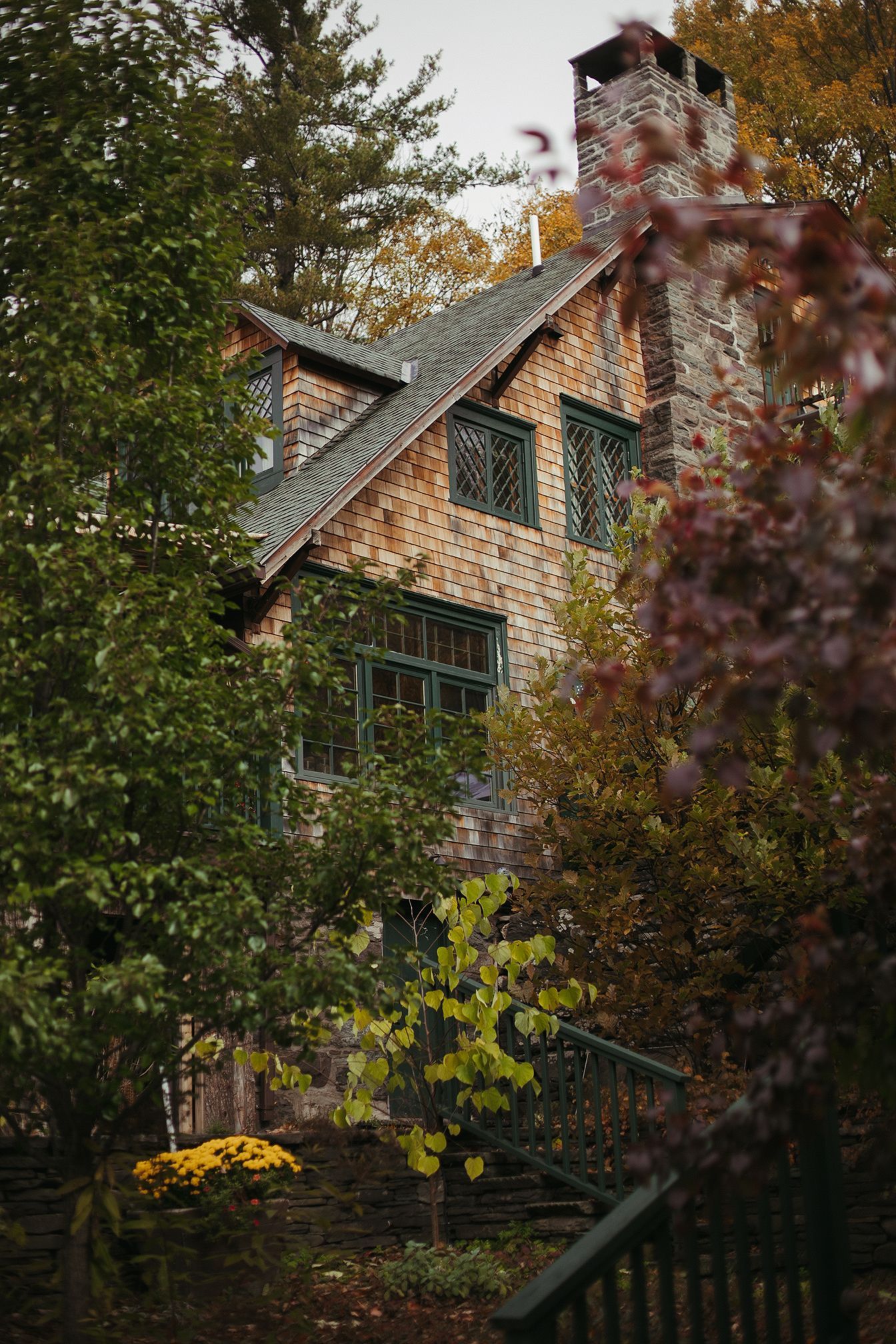 A large house with a chimney is surrounded by trees and bushes.