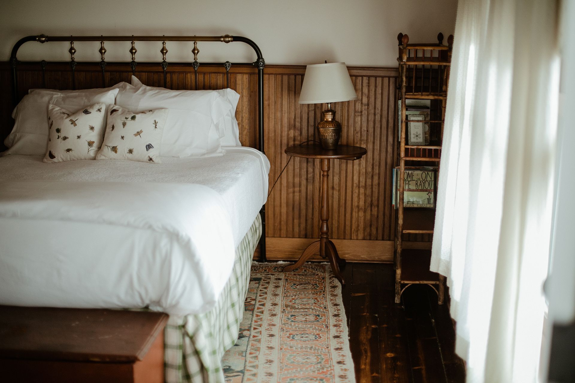 A bedroom with a bed , nightstand , lamp and rug.