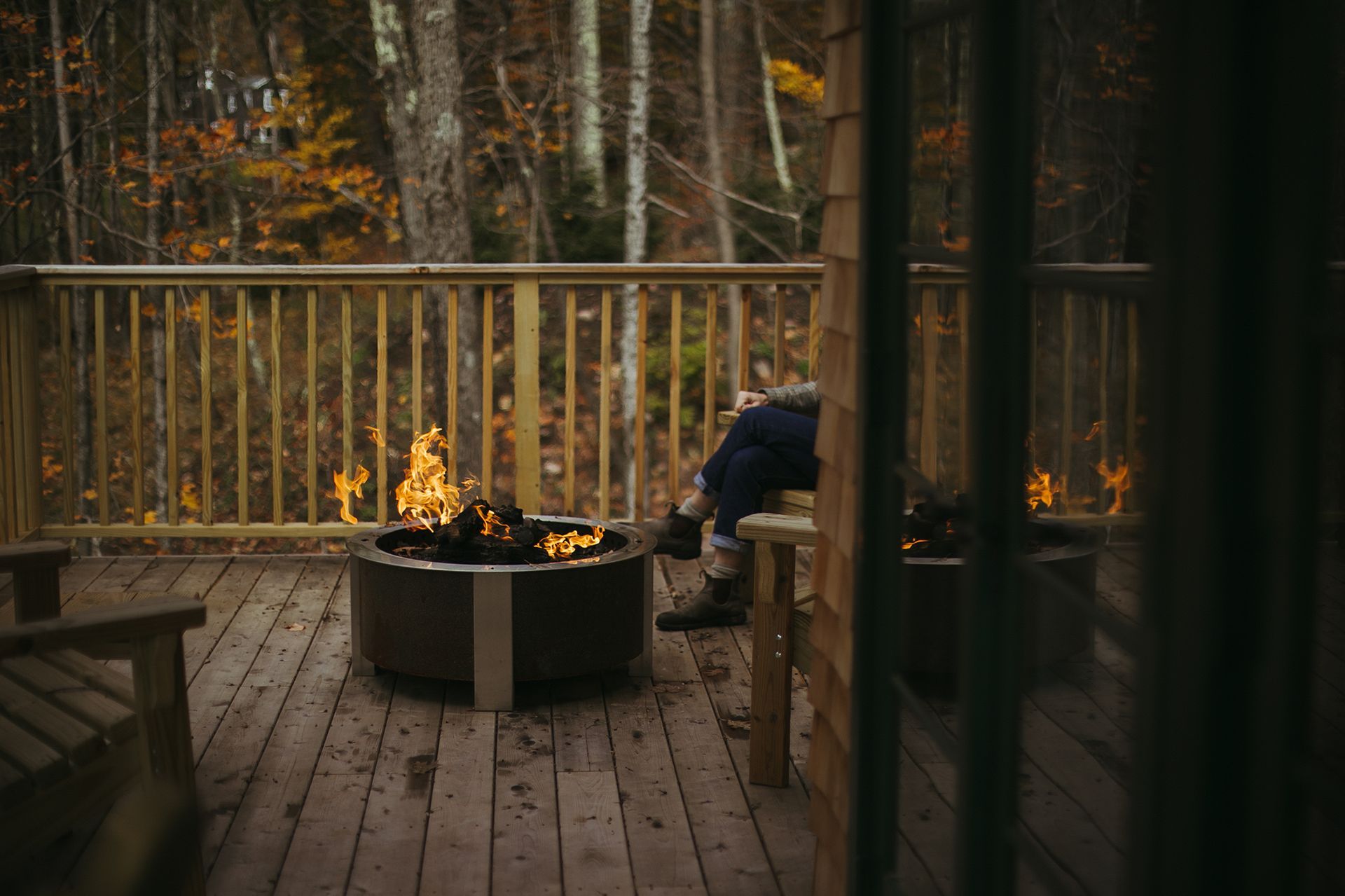 A person is sitting on a deck next to a fire pit.