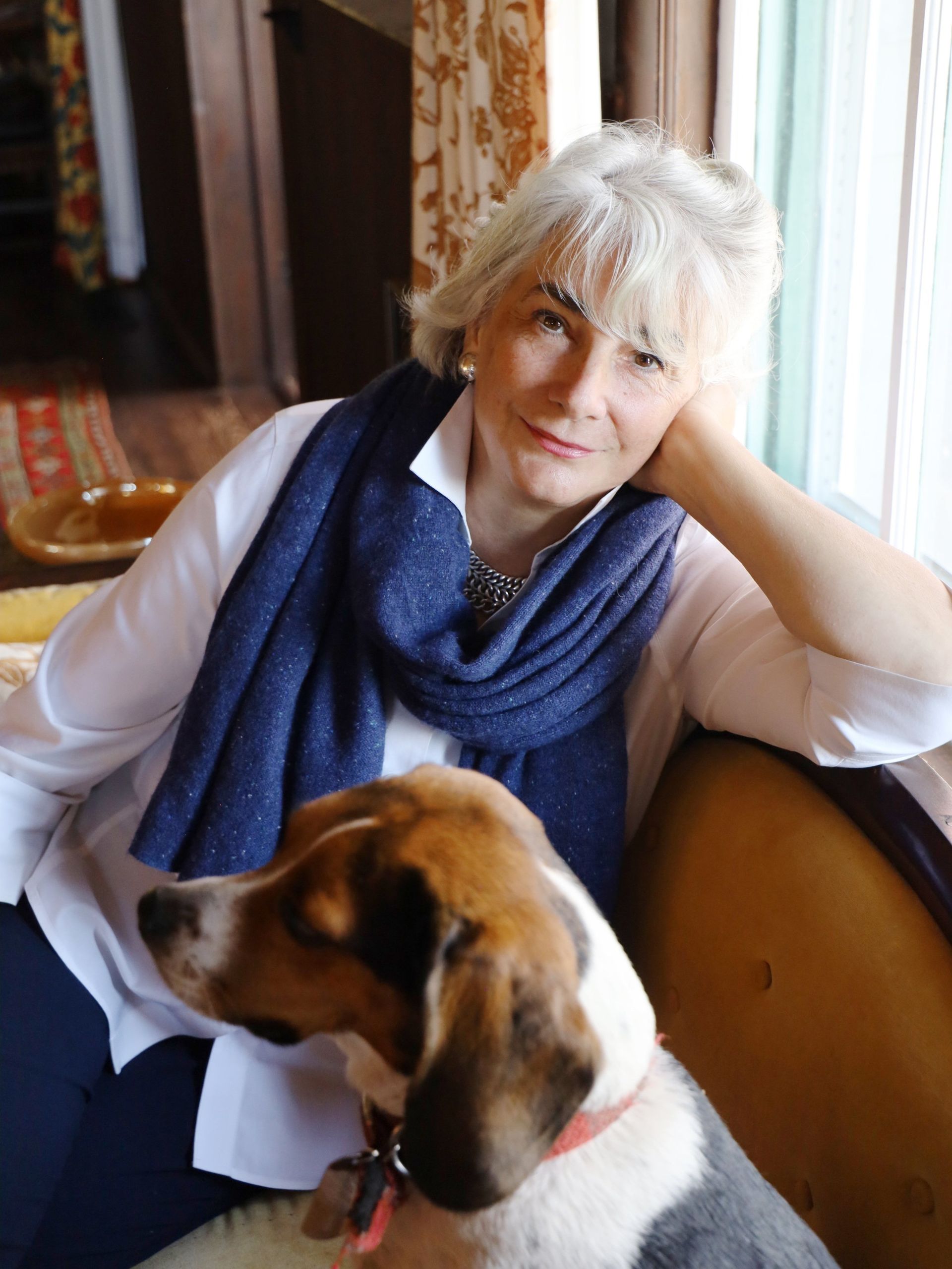 A woman wearing a blue scarf is sitting next to a dog