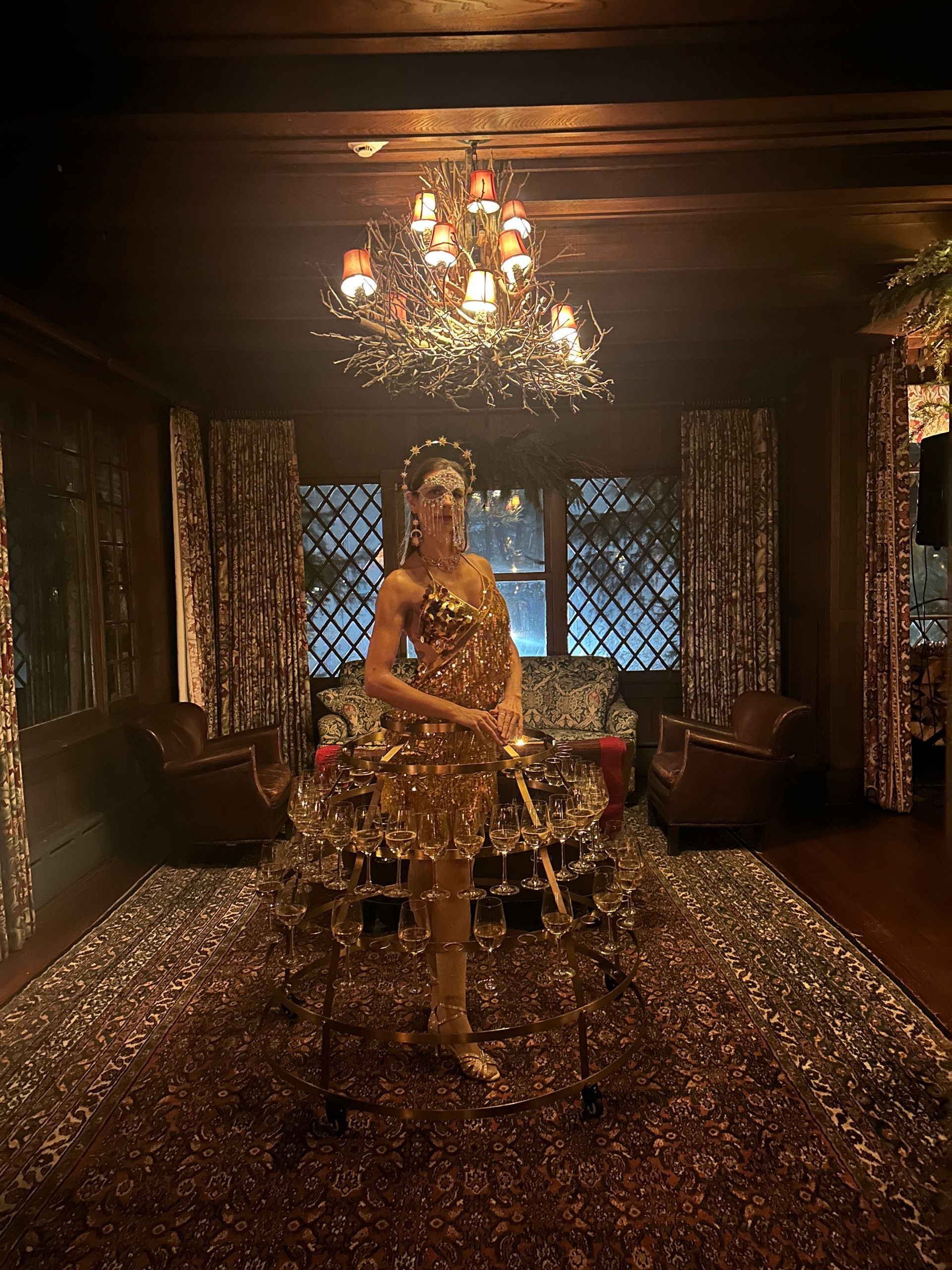 A woman in a gold dress is standing in a room covered in confetti.
