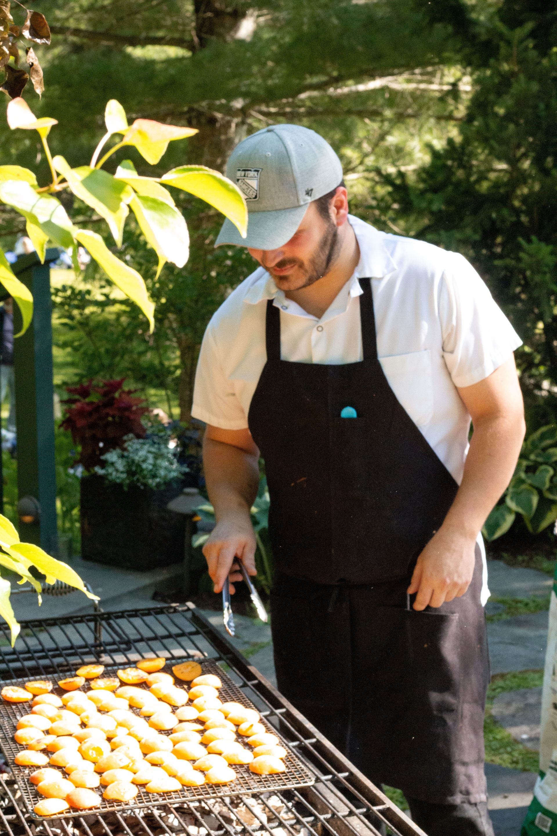 Man grilling food outdoors on a barbecue in a sunny backyard