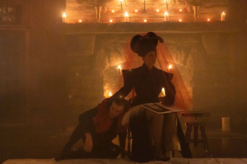 A woman is sitting on a man 's lap in a dark room with candles.