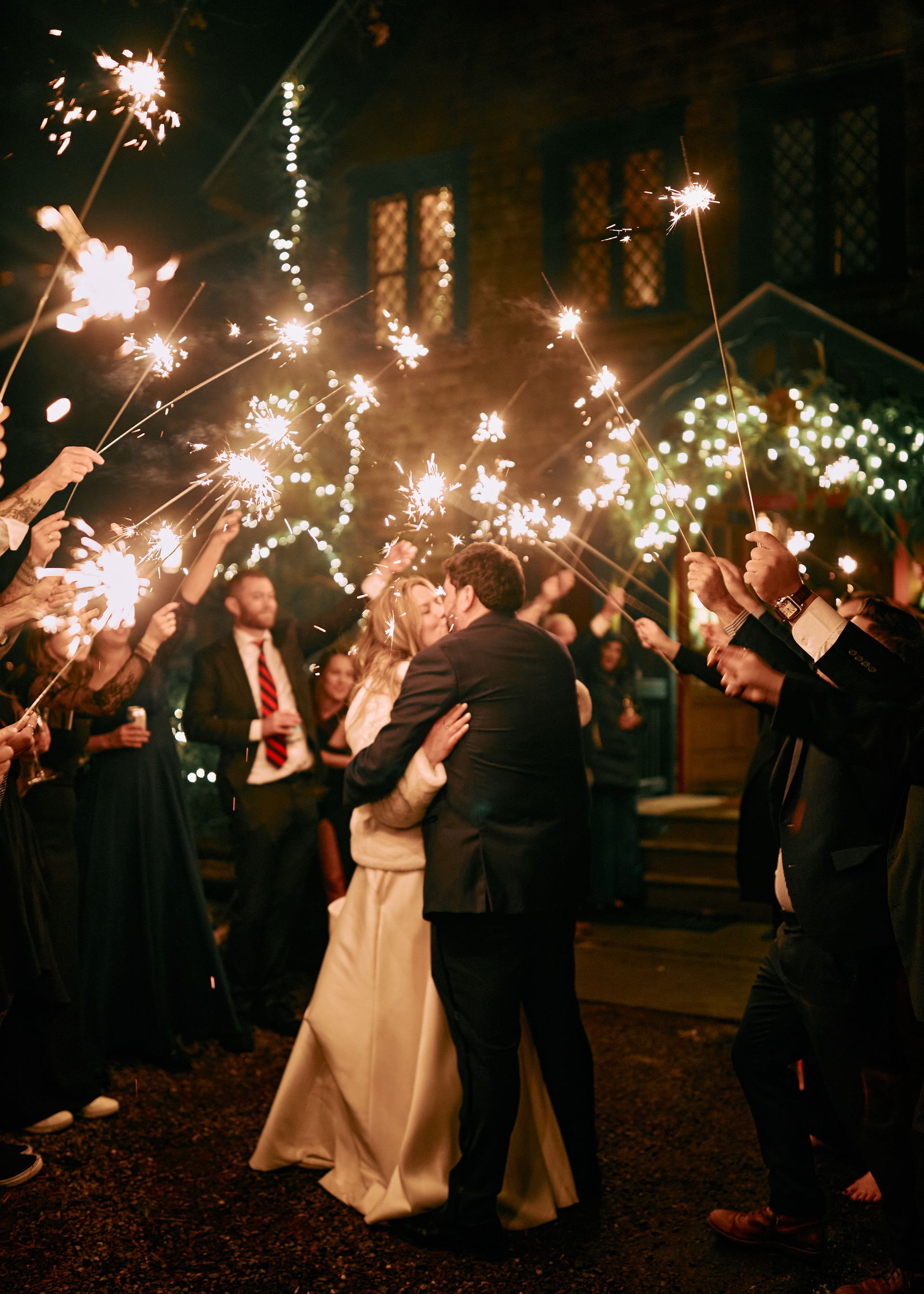 A bride and groom kissing under sparklers at their wedding reception.