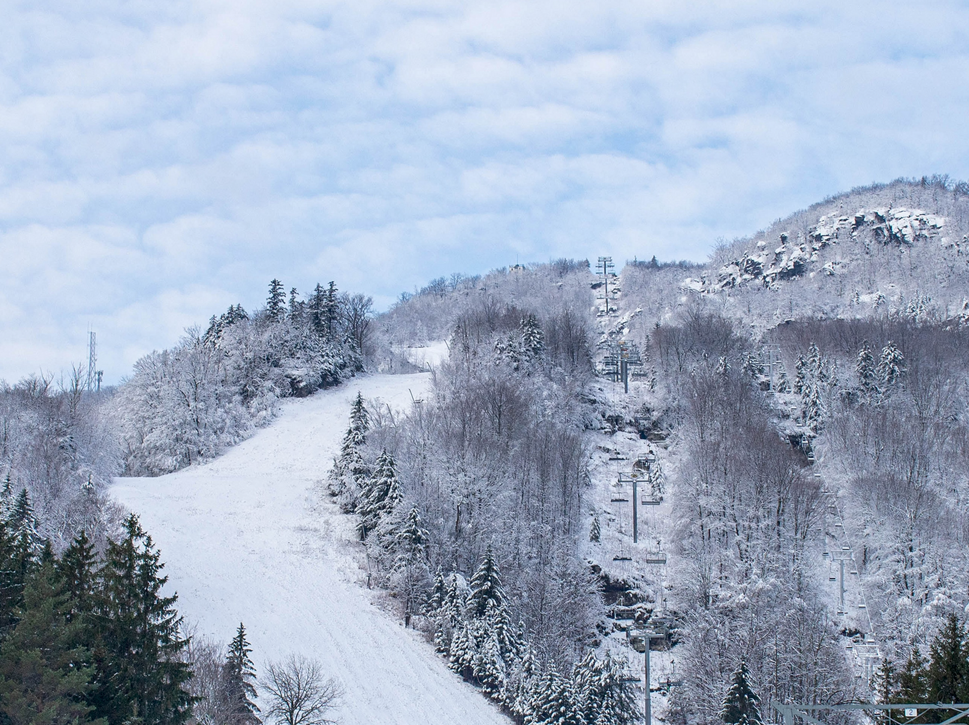 A ski lift is going up a snow covered mountain