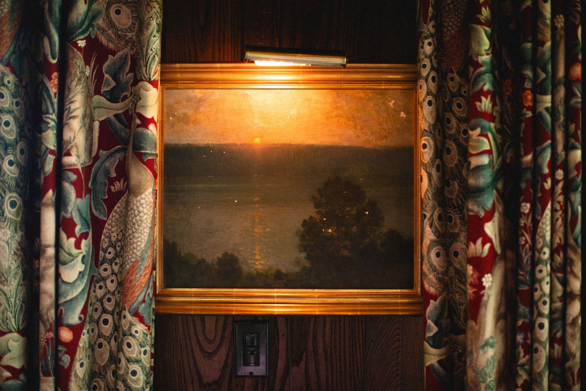 A painting is hanging on a wall in a room with curtains.