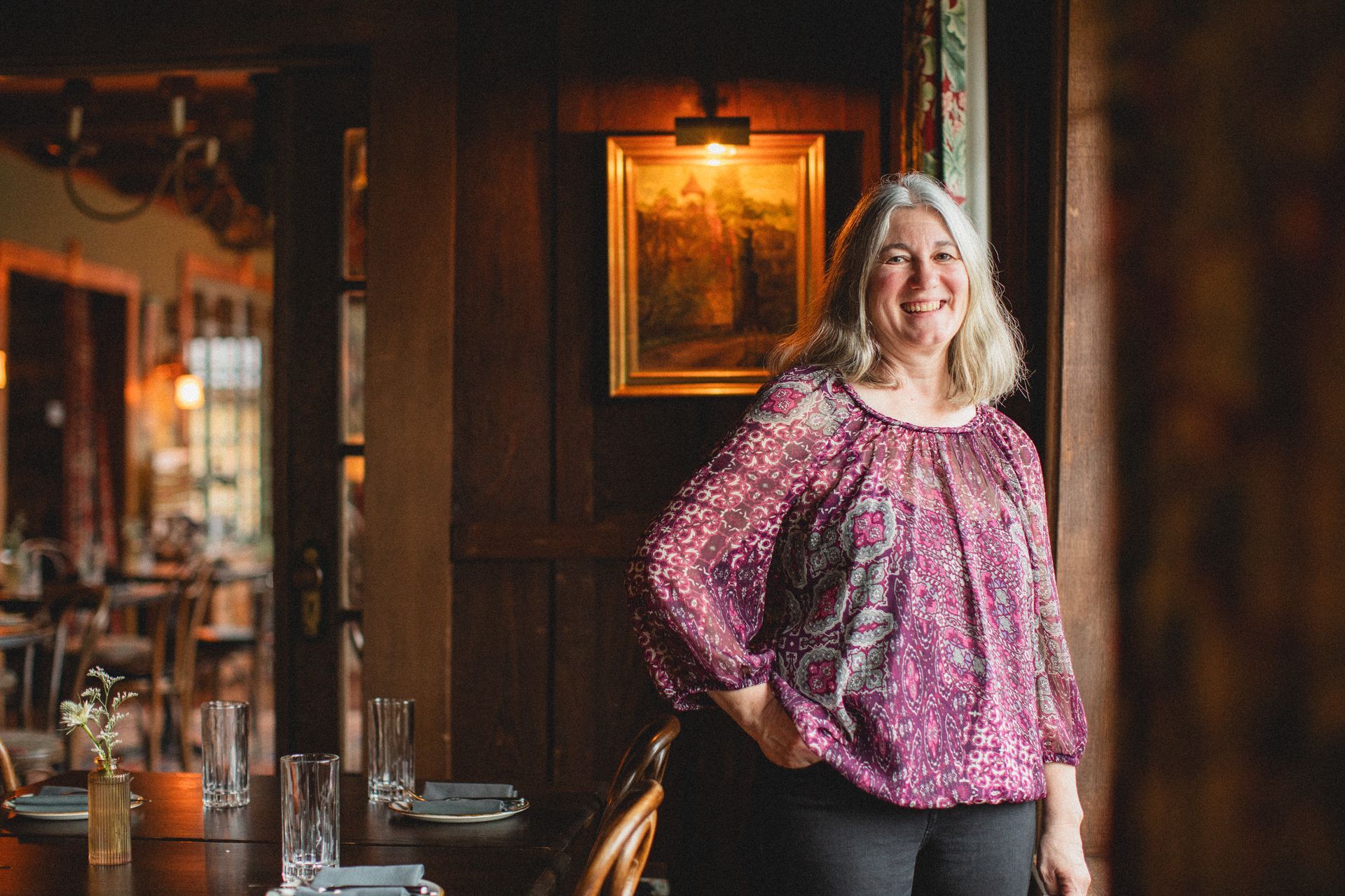 A woman in a purple shirt is standing in a restaurant.