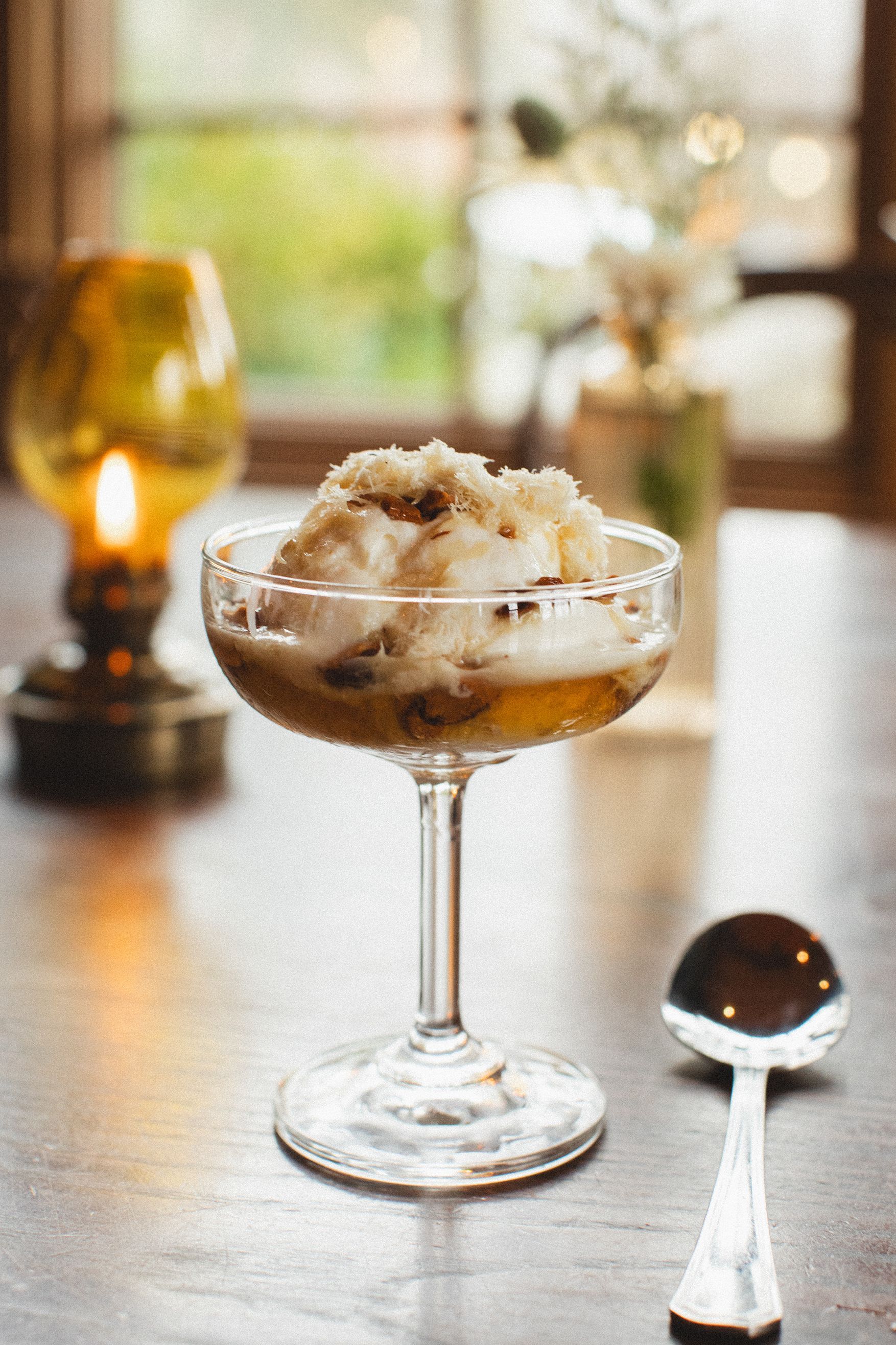 A glass of ice cream is sitting on a table next to a spoon.
