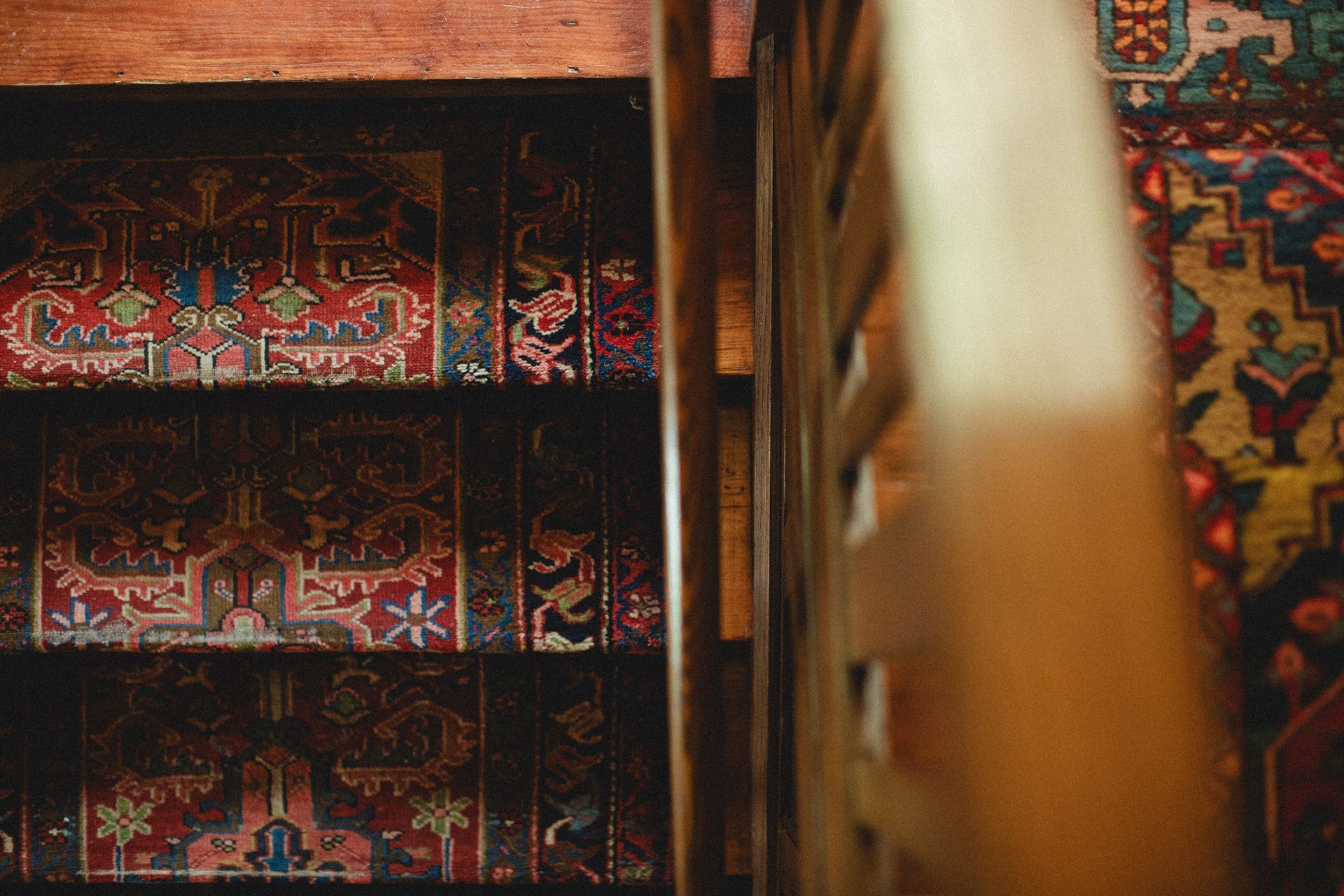 A bookshelf filled with books and a rug in a library.