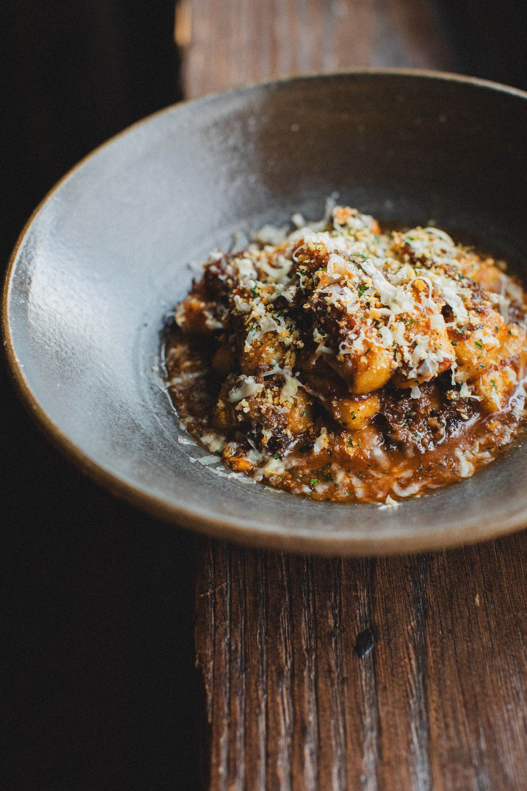 A bowl of food is sitting on a wooden table.