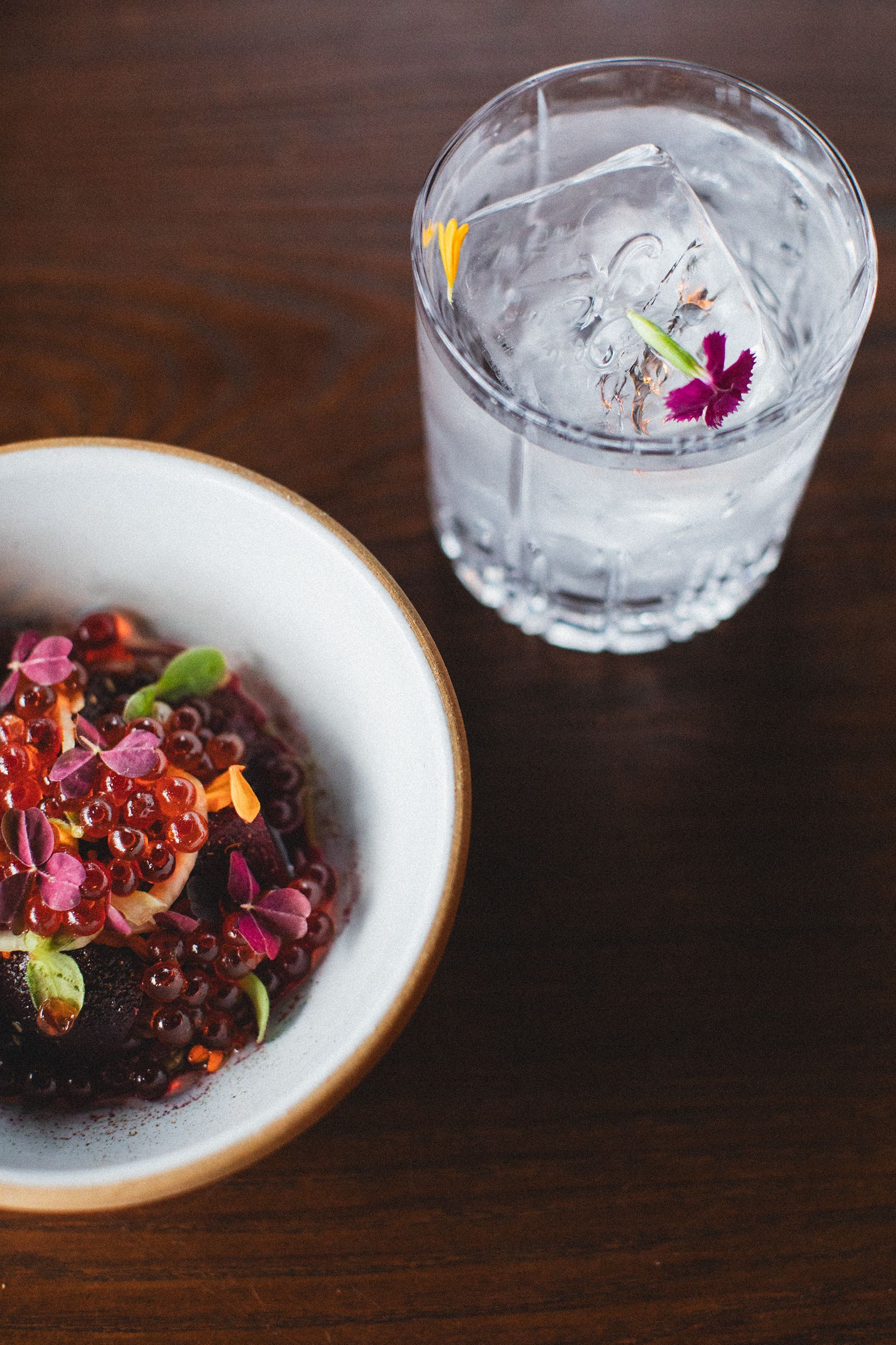 A bowl of food and a glass of water on a table.