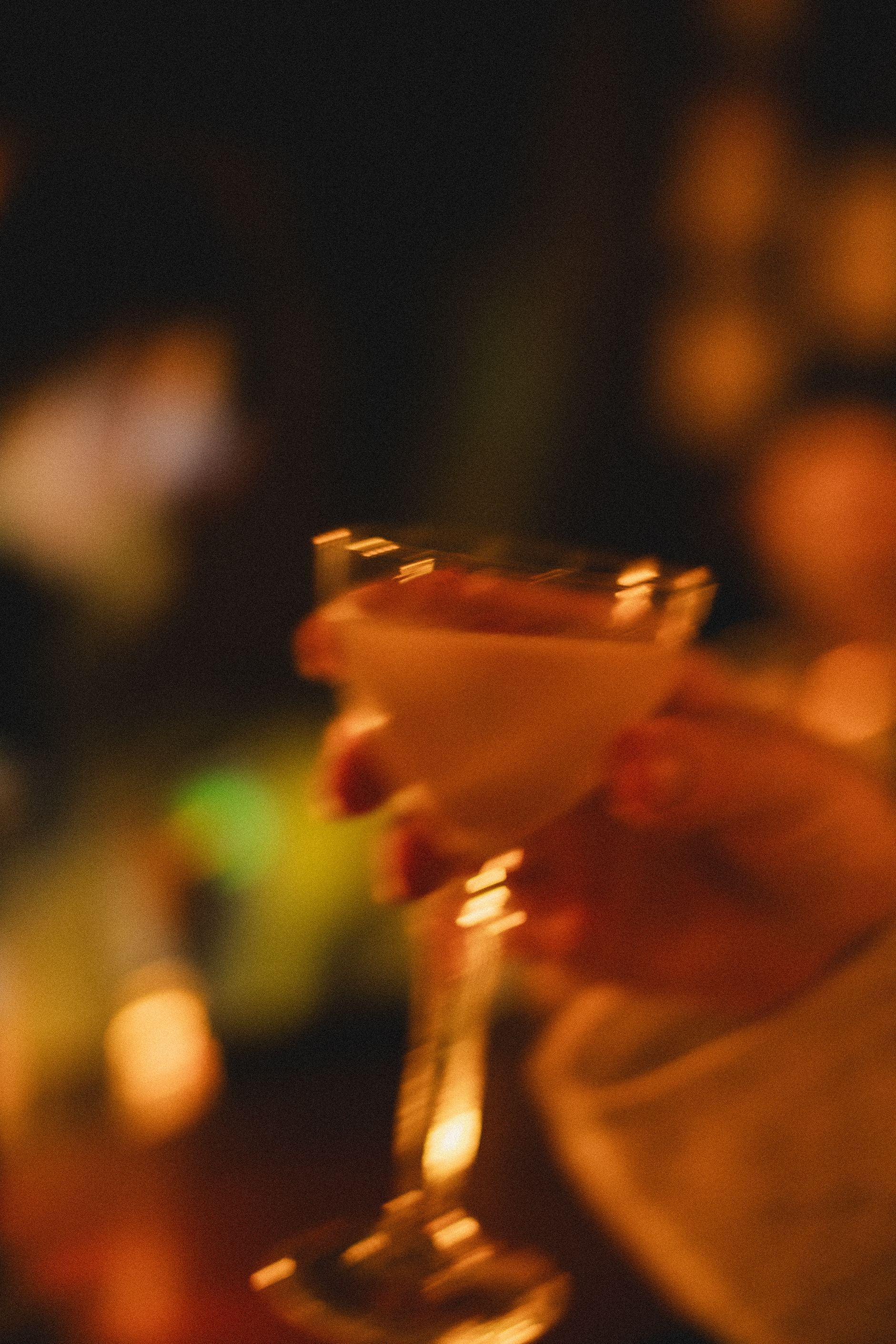A blurry picture of a person holding a martini glass.