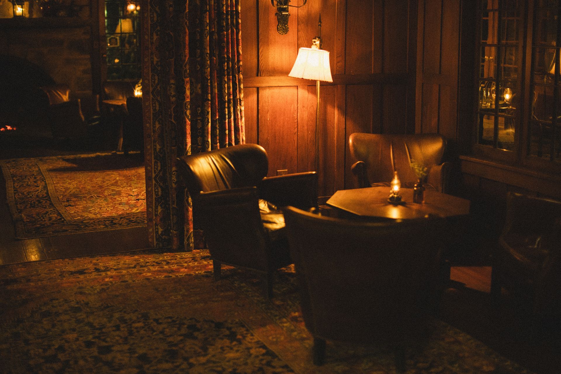 A dark room with a table and chairs and a lamp.