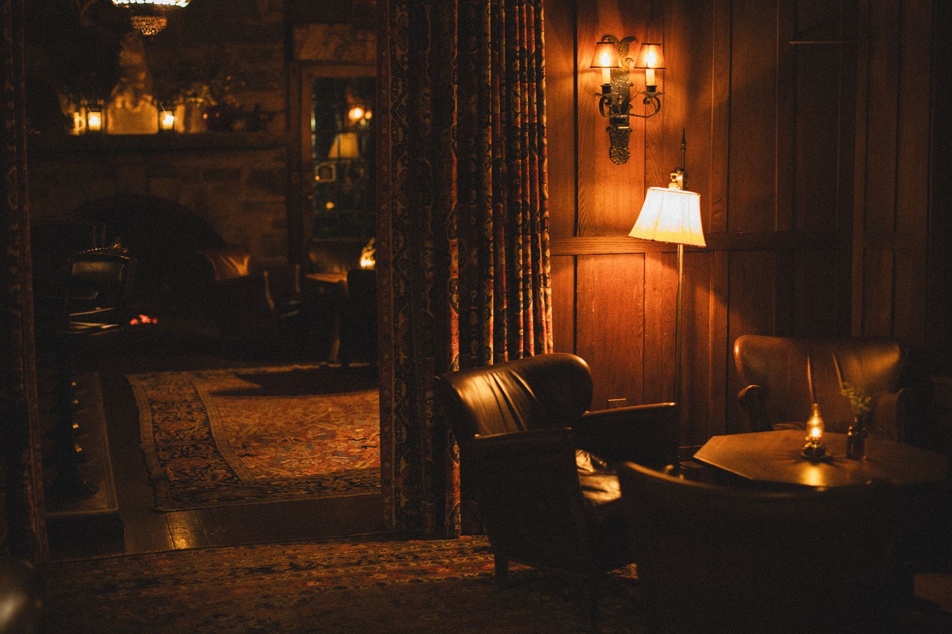A dark room with chairs , a table and a lamp.