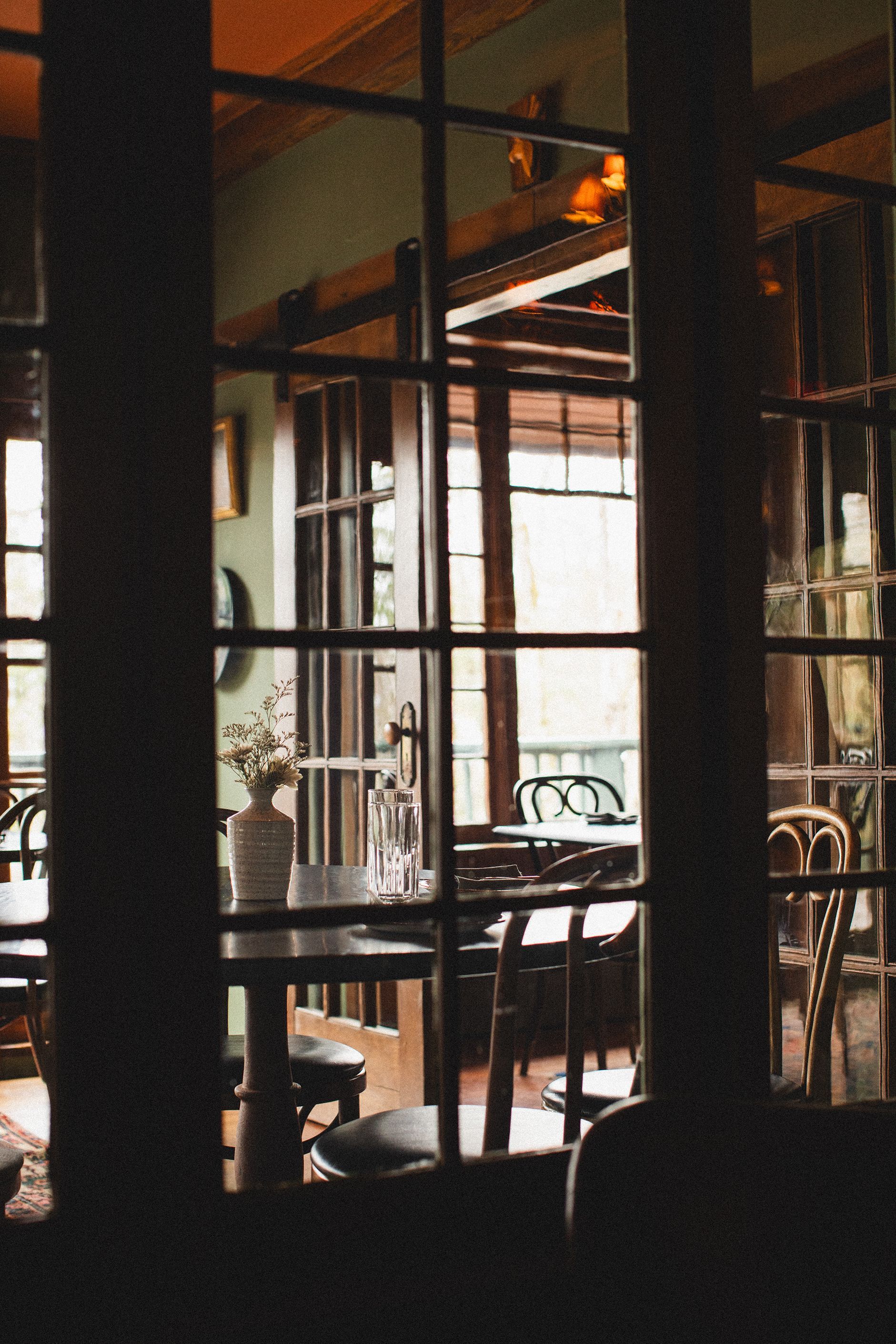 A restaurant with tables and chairs behind a glass door